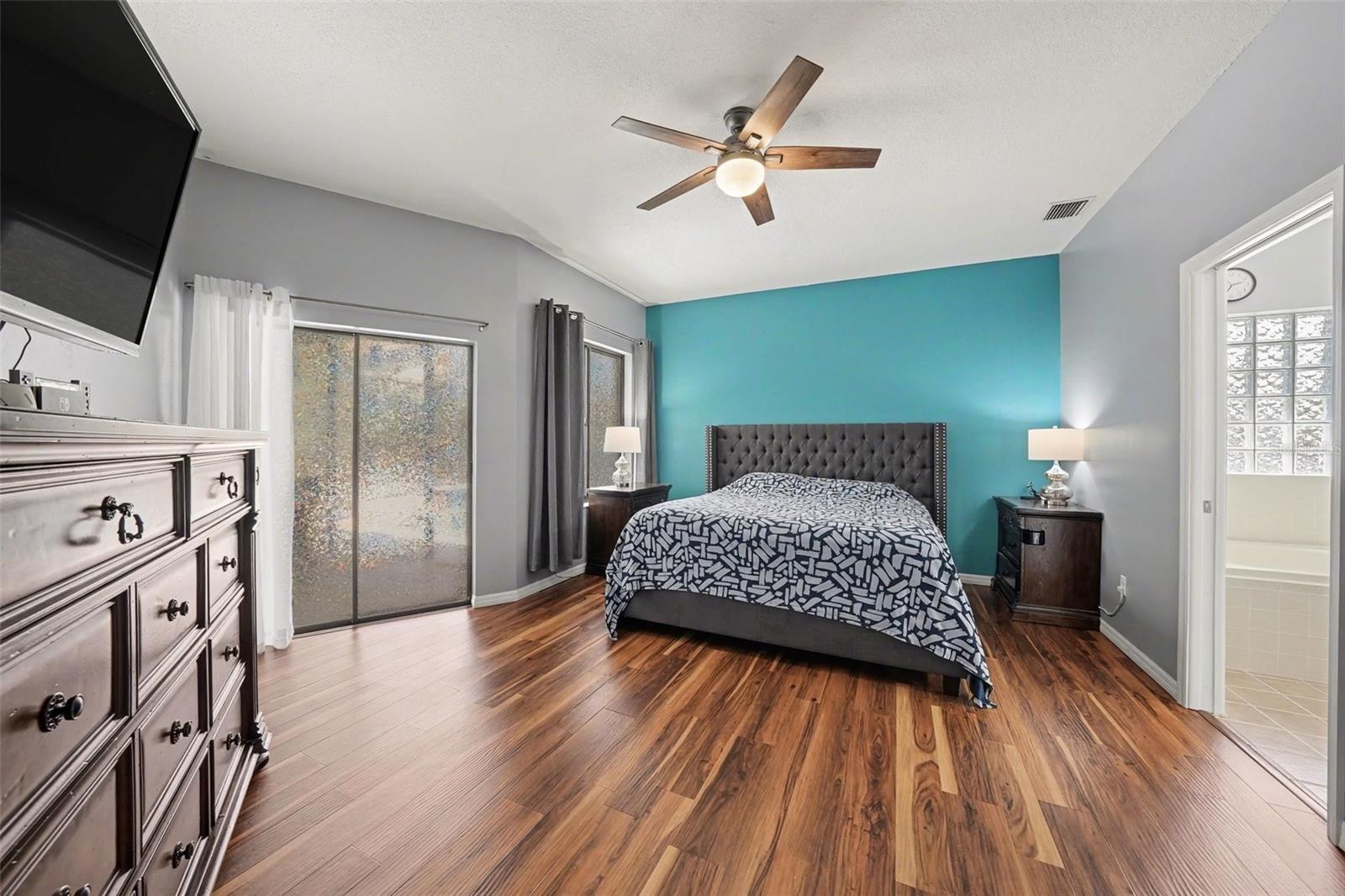 The primary bedroom is so spacious! And you can't beat the walk-in closet and private sliders to the pool