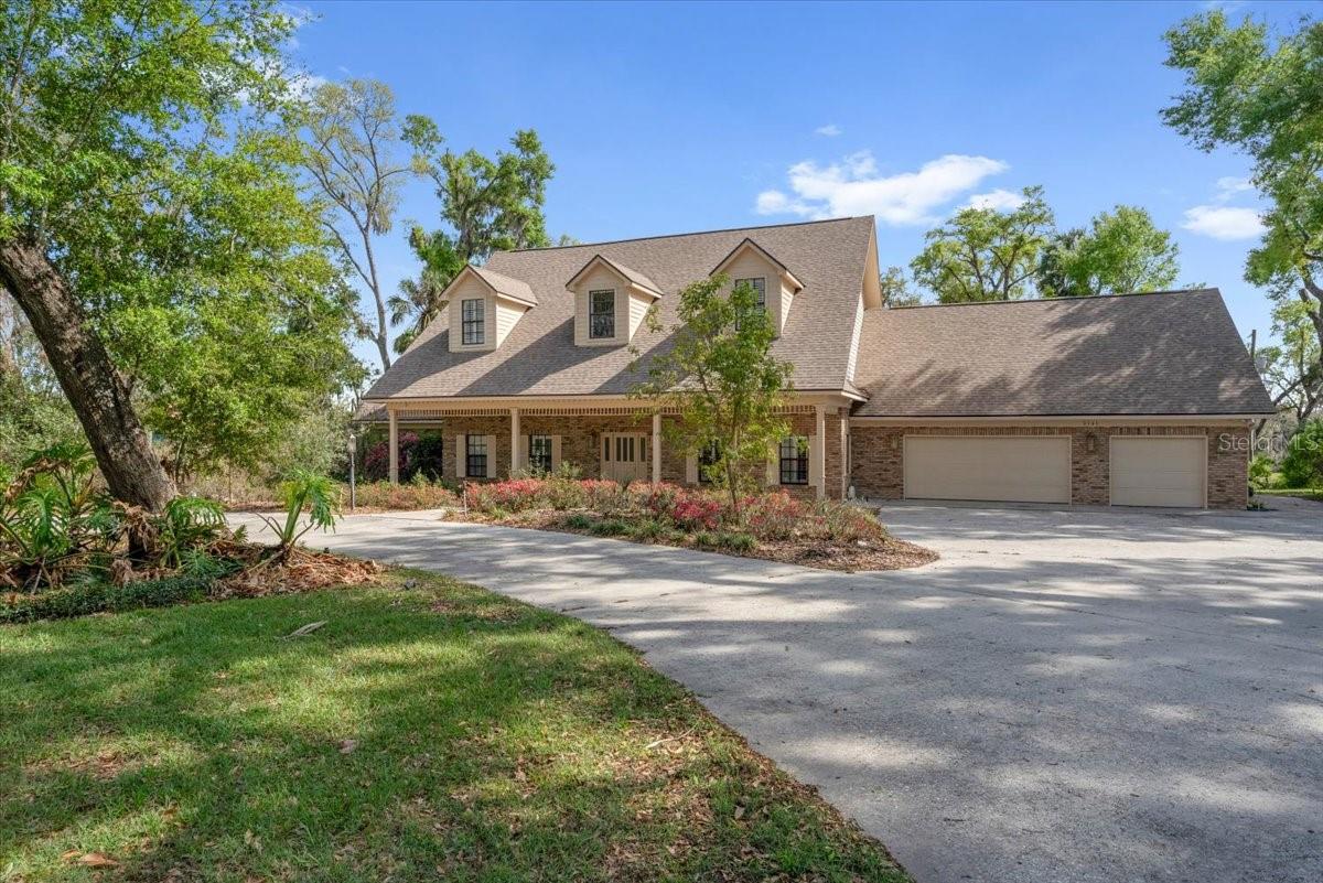Classic brick exterior with dormer windows, and sweeping driveway.