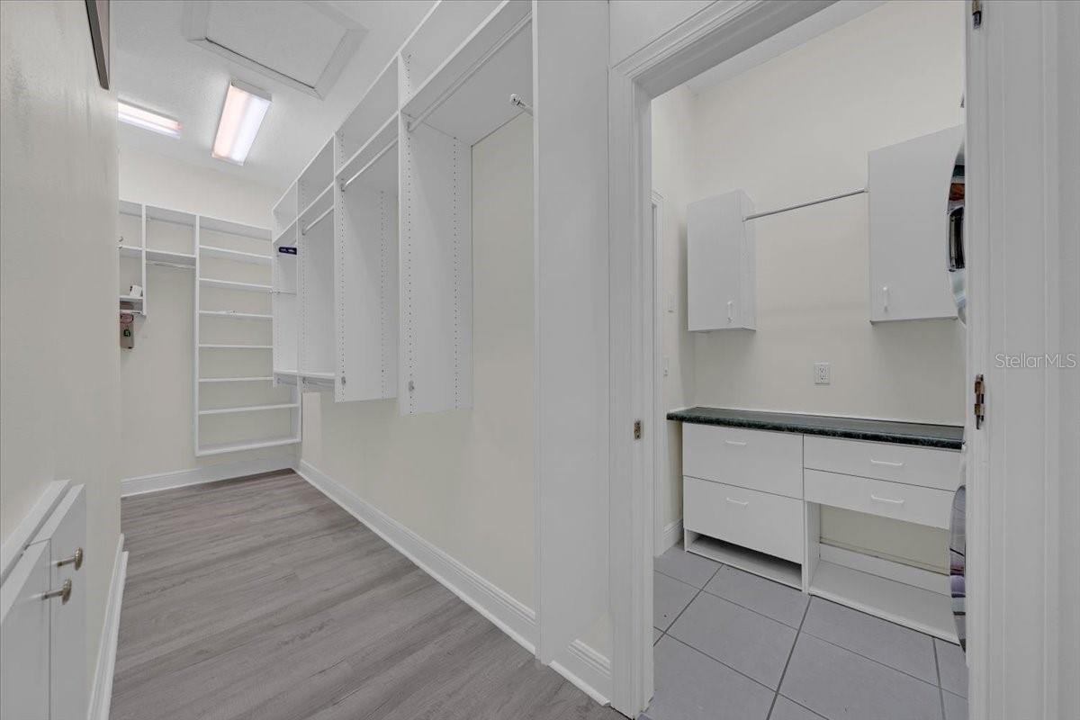 Huge custom closet with built-in shelving, plus adjacent laundry room with cabinets and counter.