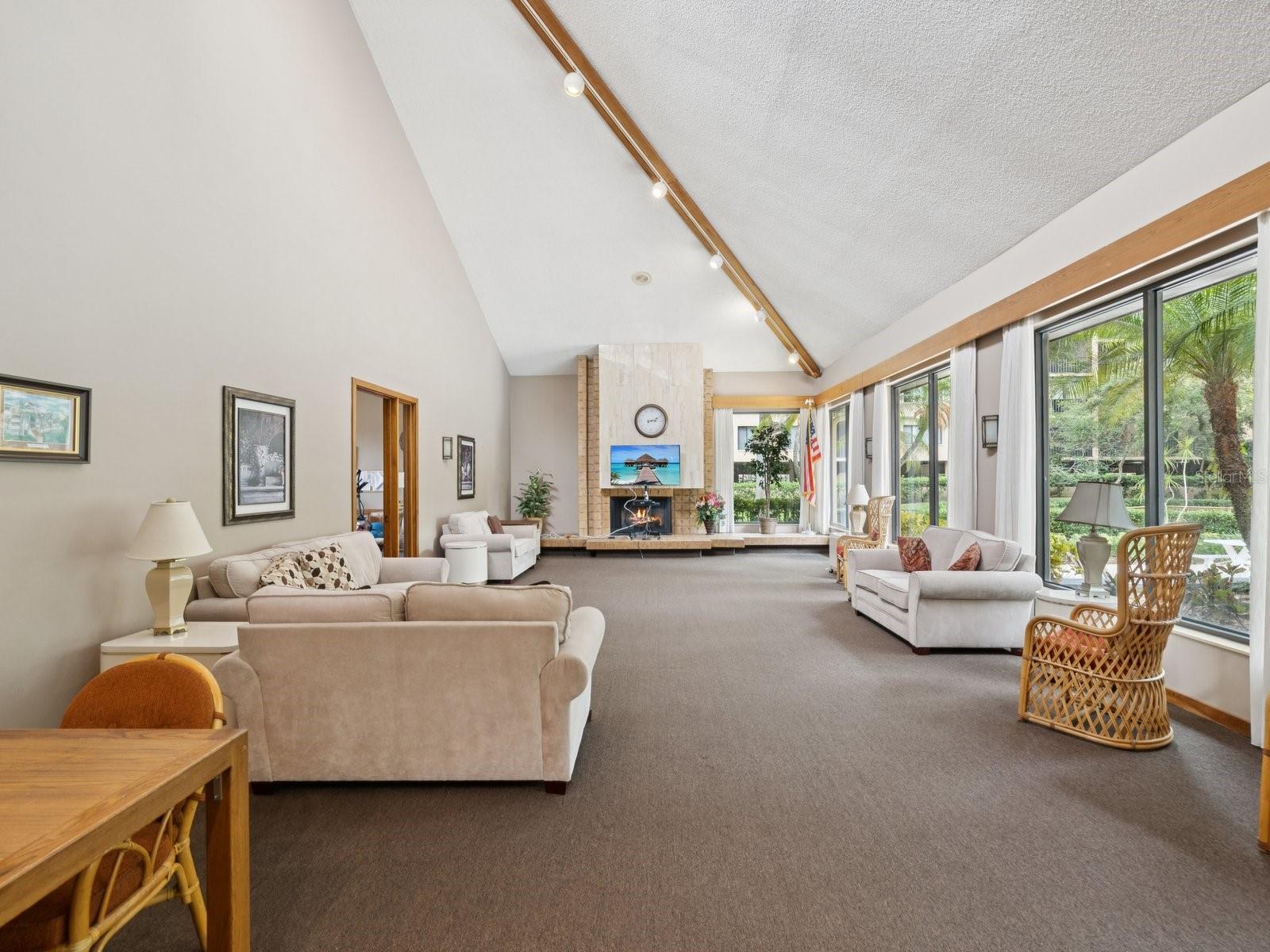 Gathering room in Clubhouse views of pool and cozy fireplace