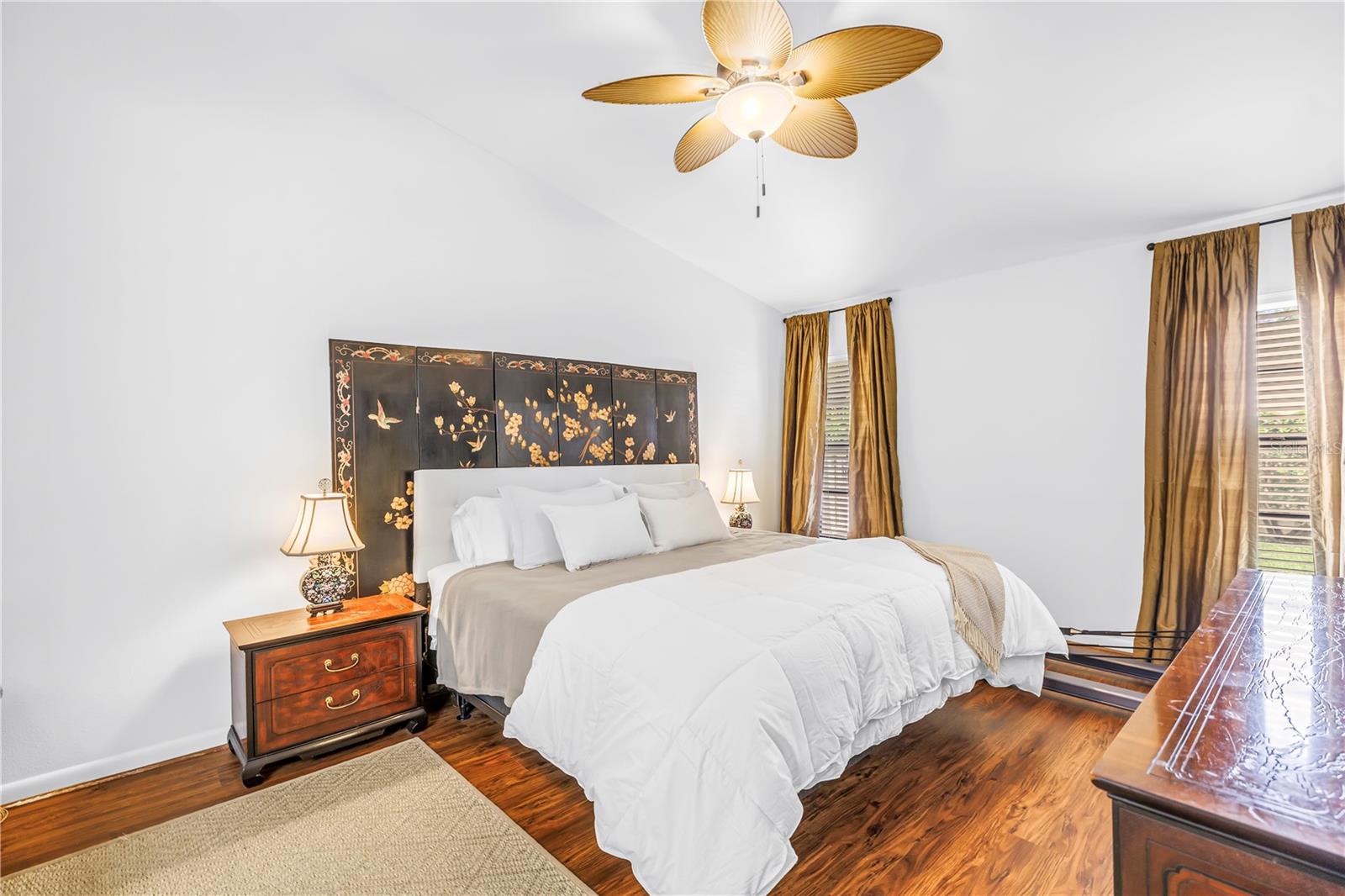 Primary Suite with Wood Grain Flooring Soaring Vaulted Ceilings and Morning Light view of the Back Garden