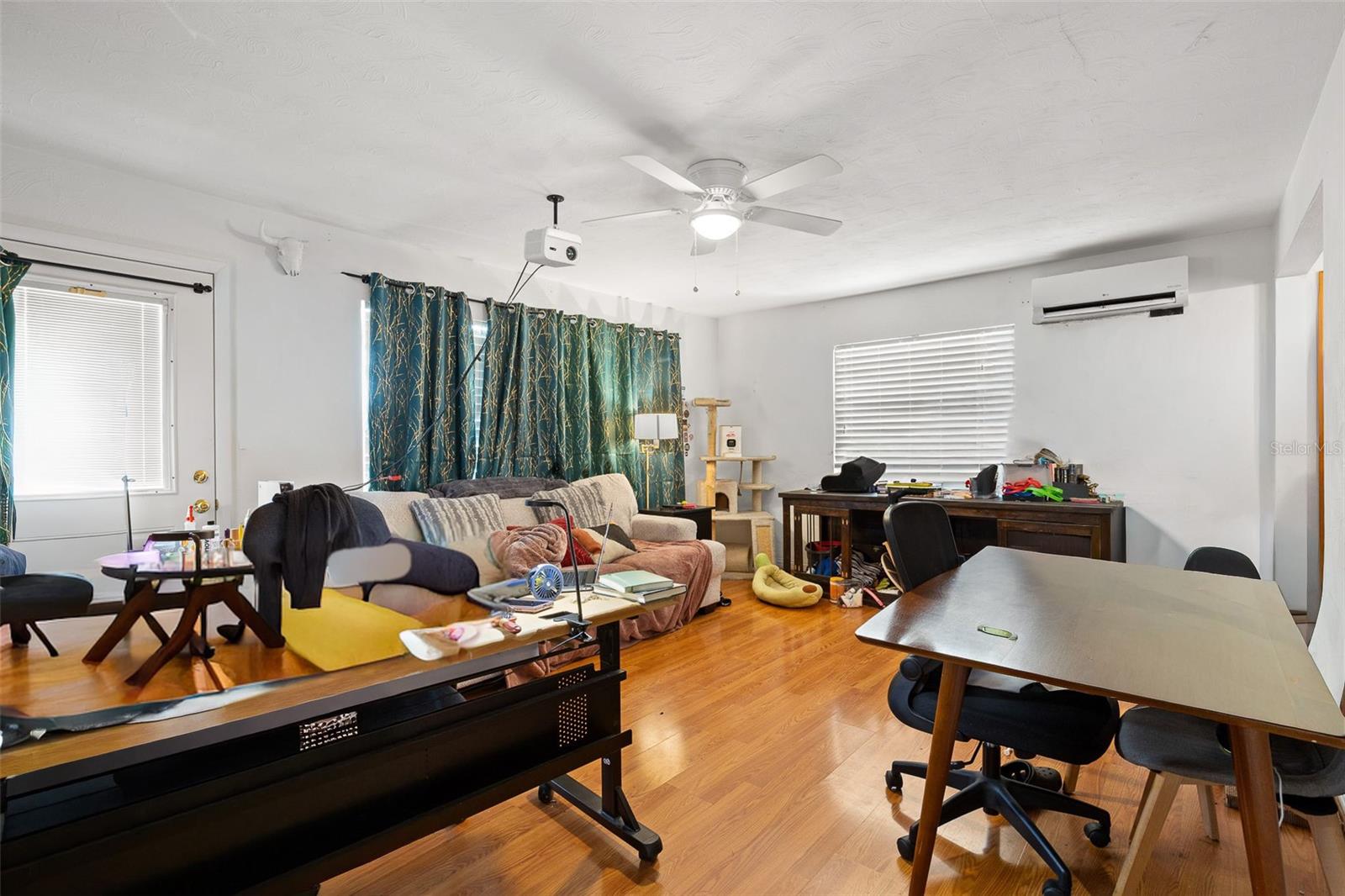 Spacious living area with wood-look laminate flooring and flexible layout options, easily accommodating both living and work-from-home setups. Natural light and an open feel make the space adaptable to a variety of needs.