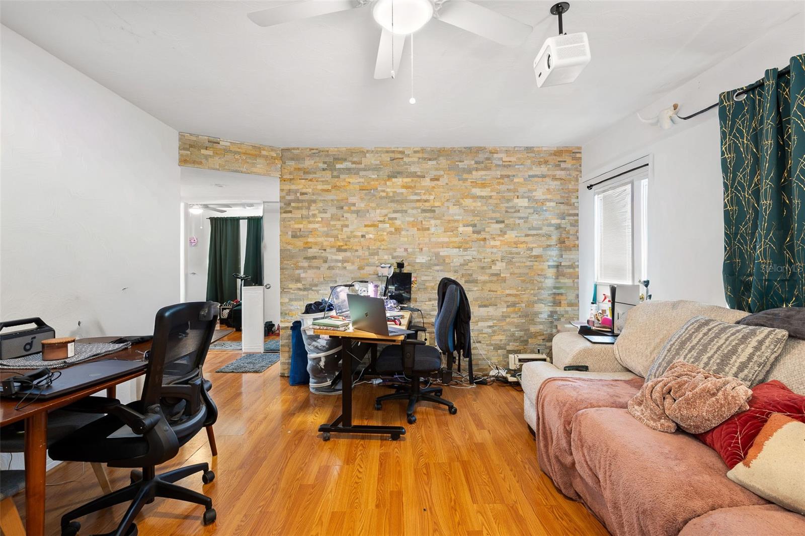 Living room features a decorative accent wall and an open layout that flows into adjacent spaces, offering flexibility for seating, office use, or creative configurations.