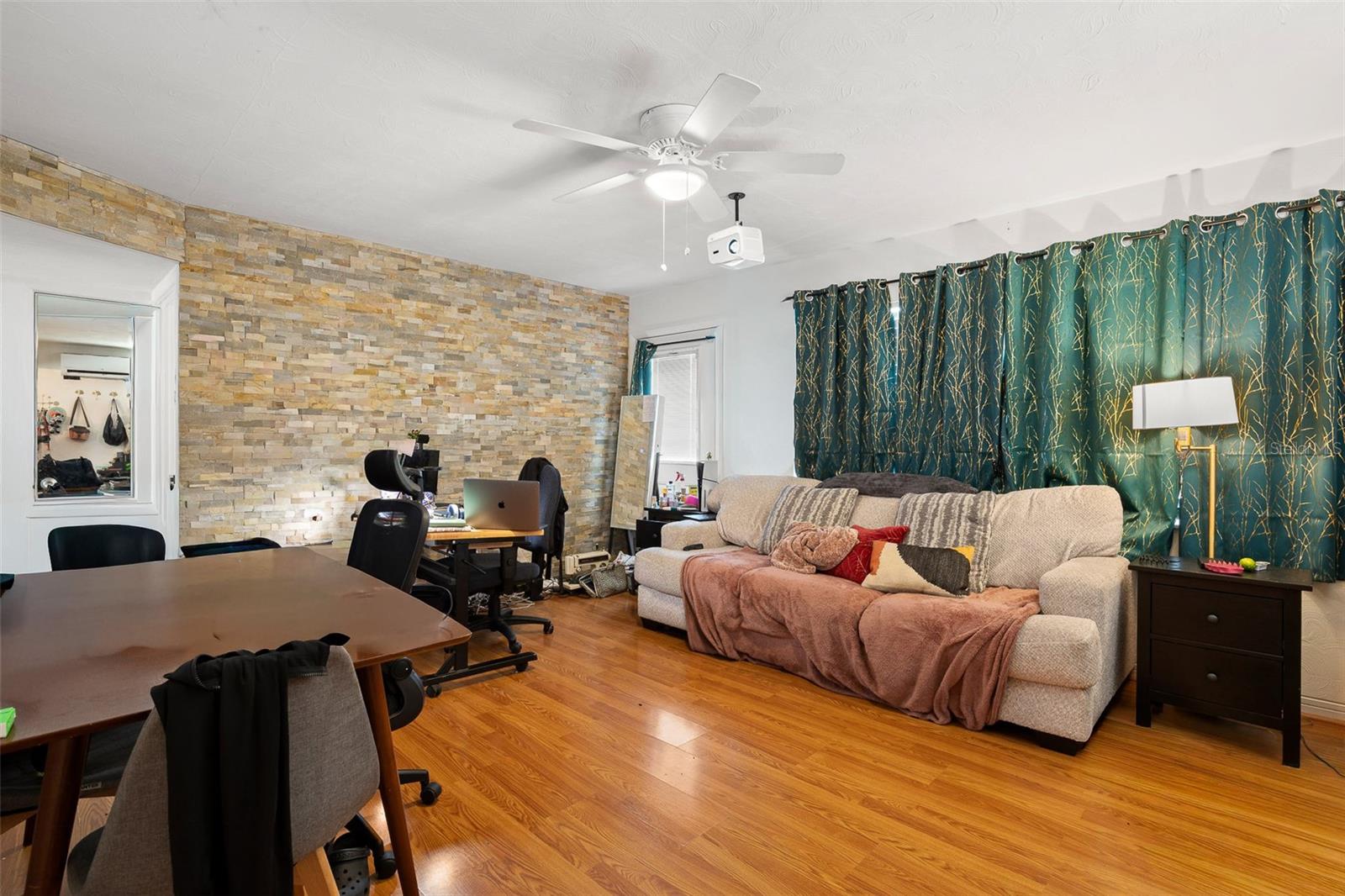 Bright and comfortable living space with multiple windows for natural light, a ceiling fan with light kit, complemented by wood-look laminate flooring and a layout that supports both relaxation and everyday living.