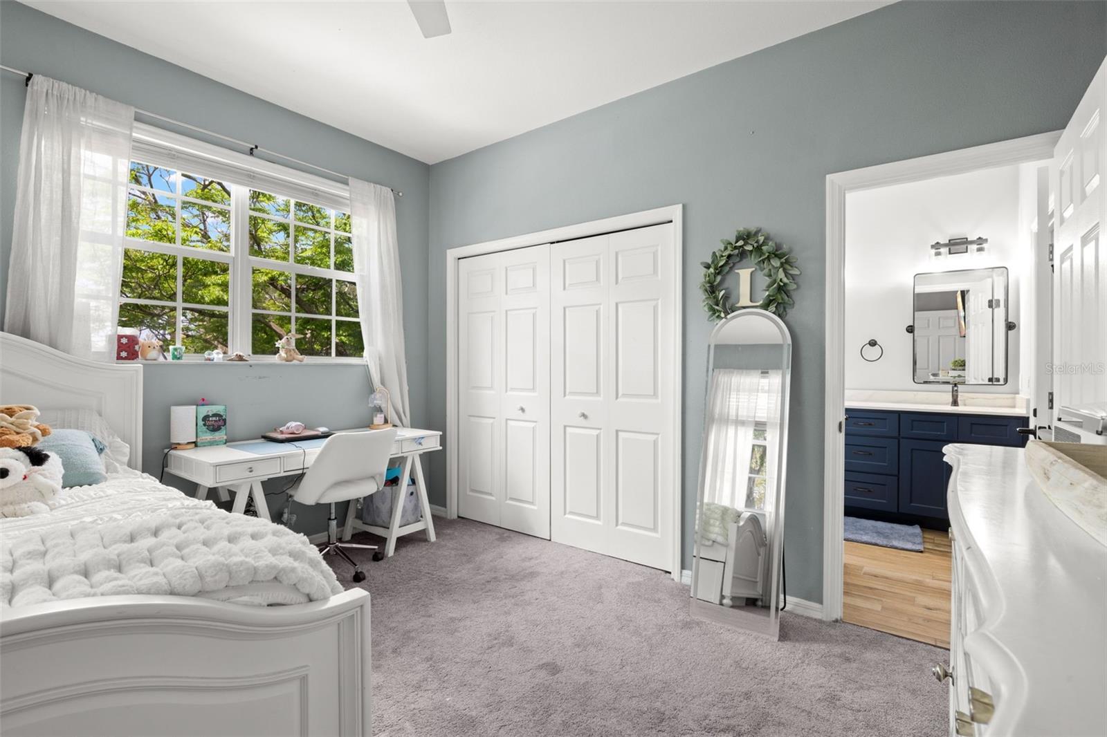 Bedroom 2 featuring plush carpeting, a large window for natural light, a built-in closet, and direct access to a Jack and Jill bathroom.