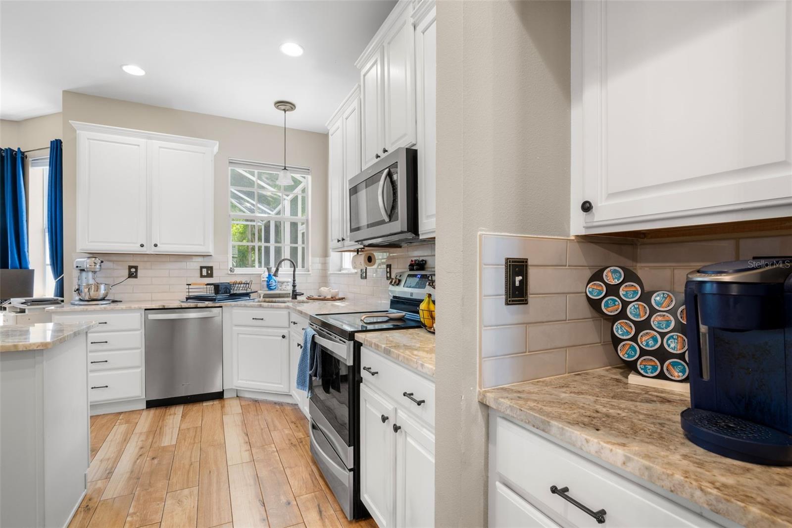he kitchen is thoughtfully designed with alabaster wood cabinetry, marble countertops, subway tile backsplash, recessed and pendant lighting.
