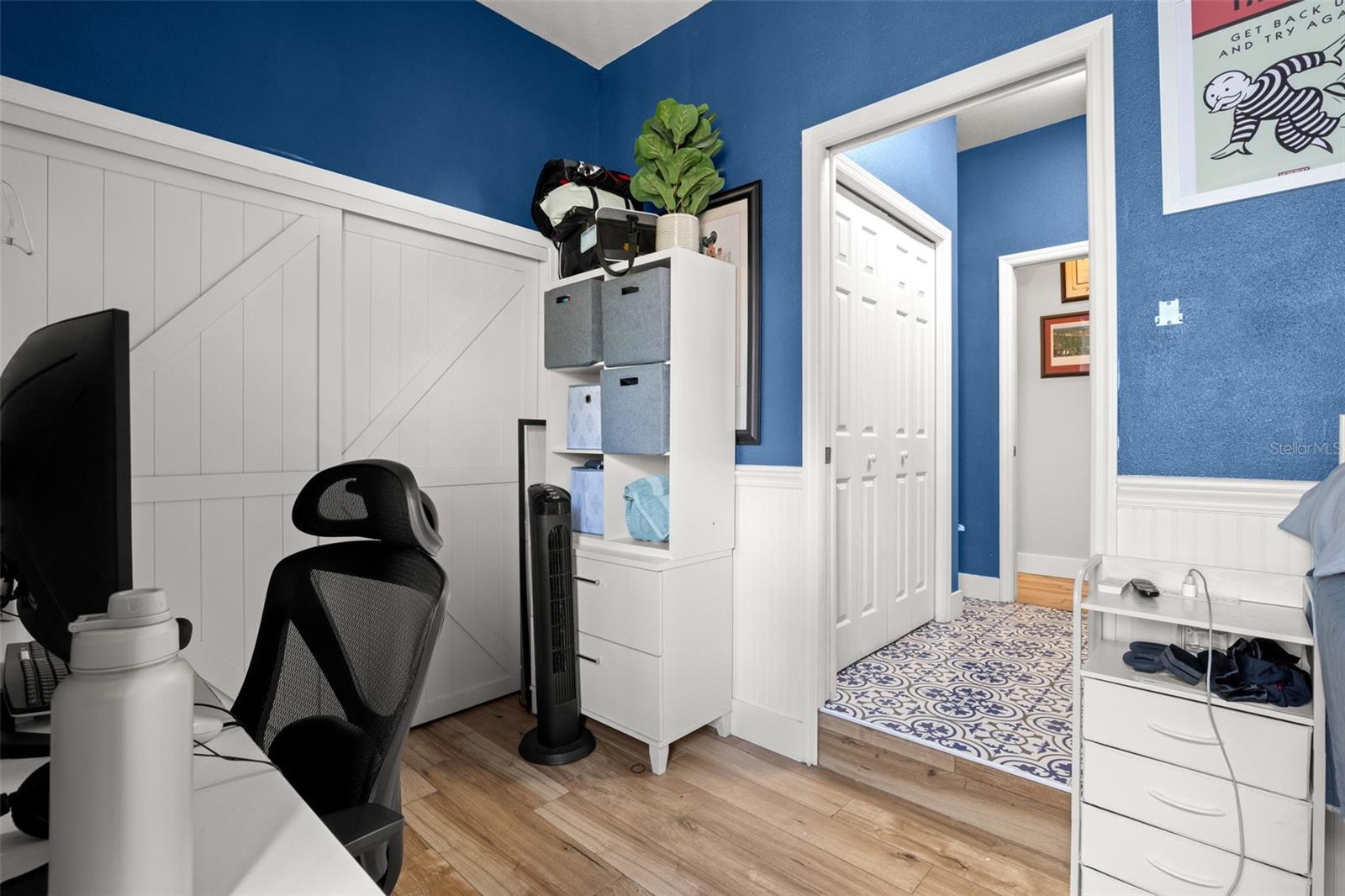 Multi-functional downstairs space ideal as a home office, guest room, or fourth bedroom, featuring wood plank flooring, board-and-batten accents, and a bold color palette