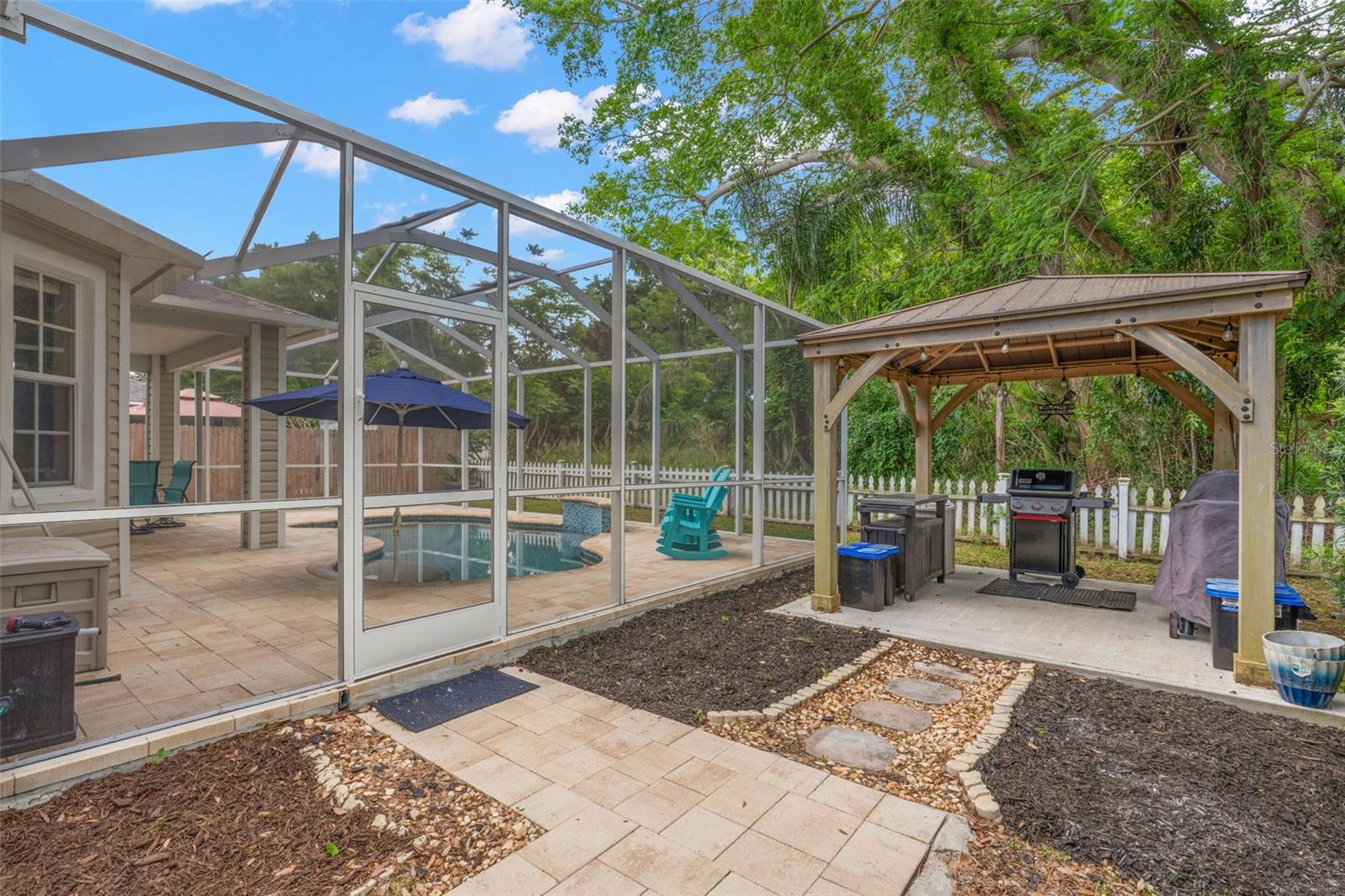 A pergola on a cement pad creates a dedicated grilling or lounge area.