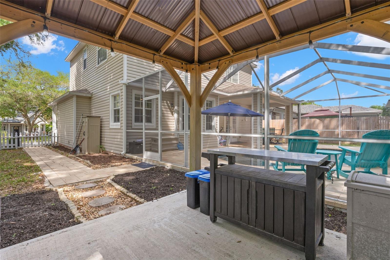 A pergola on a cement pad creates a dedicated grilling or lounge area.