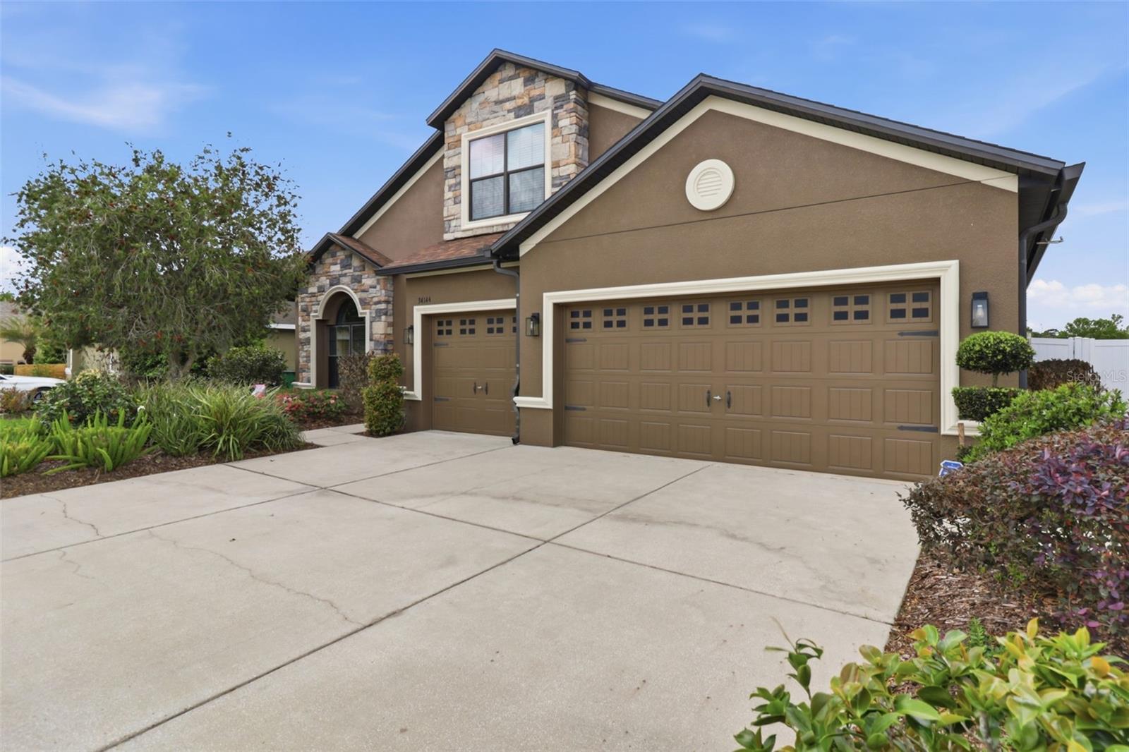 Additional front exterior view showcasing the home’s attractive elevation, stone accents, and spacious three-car garage.