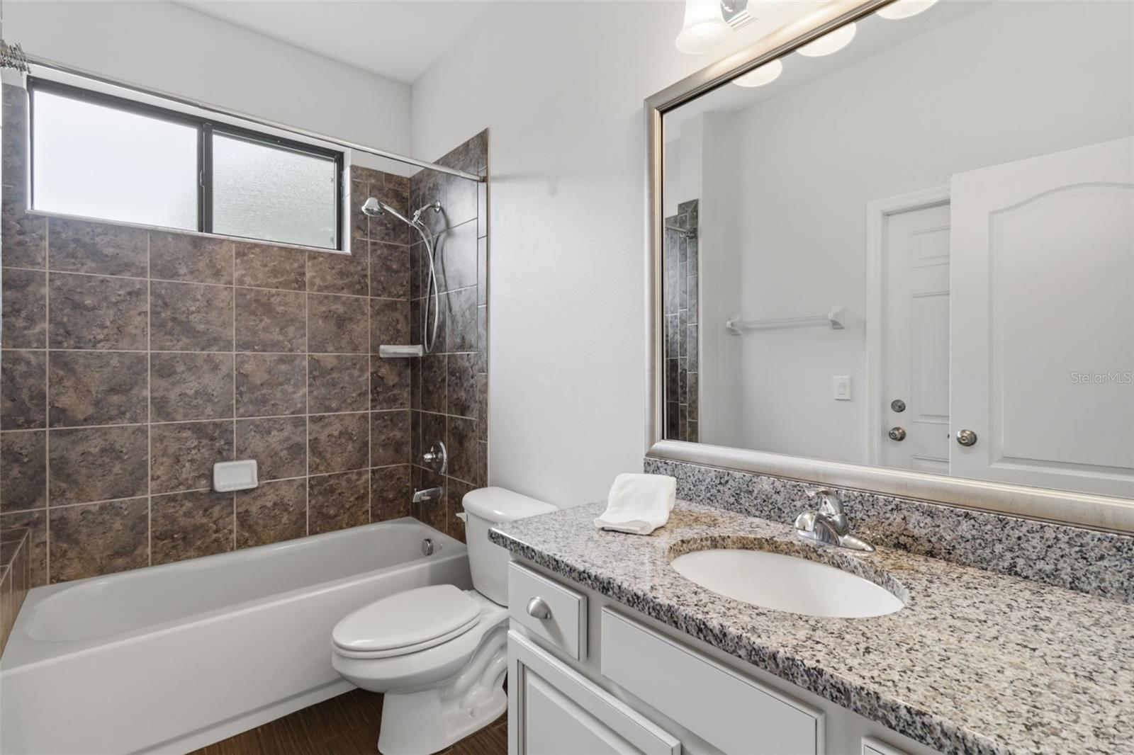 Third full bathroom featuring a tub/shower combination, granite countertop vanity, and clean, modern finishes.