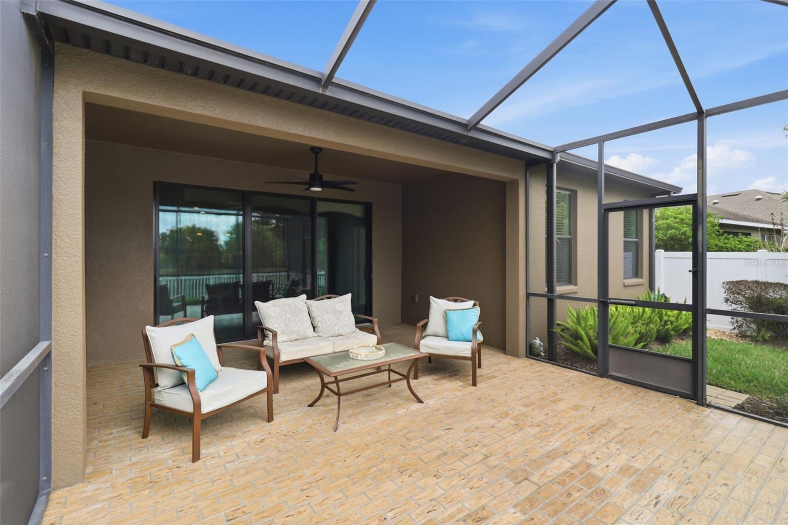 Covered and screened lanai with paver flooring, offering a spacious outdoor living area perfect for relaxing or entertaining while enjoying peaceful waterfront views.