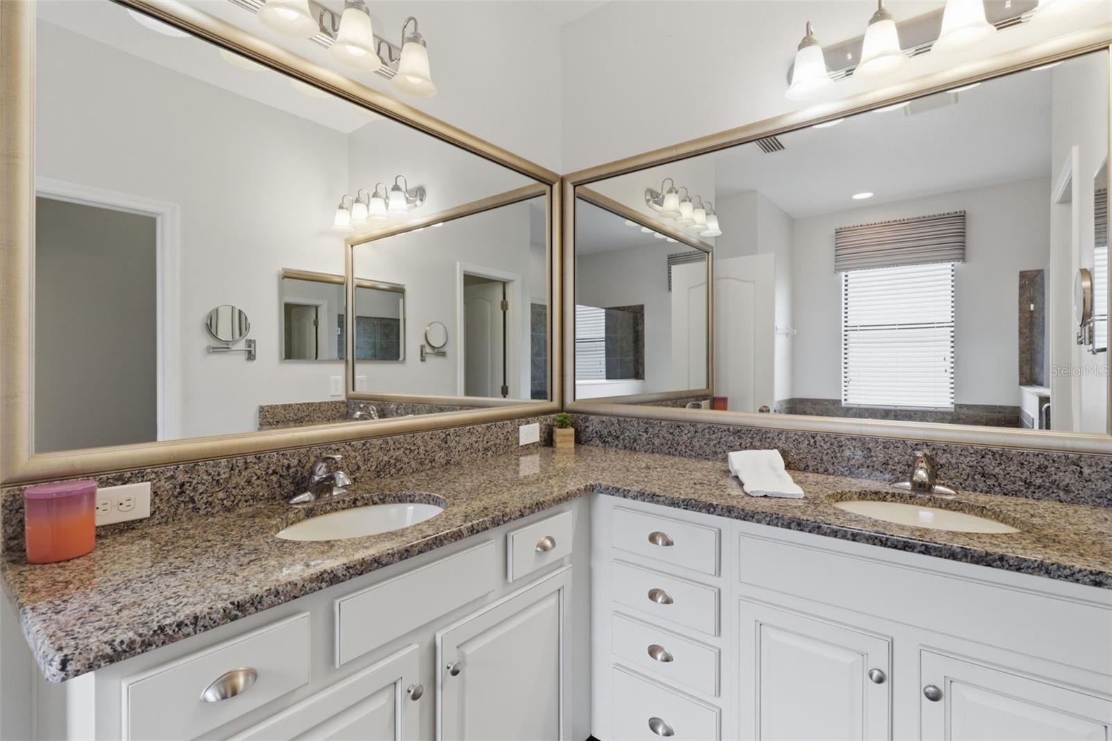 Primary bathroom with dual-sink vanity, granite countertops, and ample storage, offering both functionality and style.