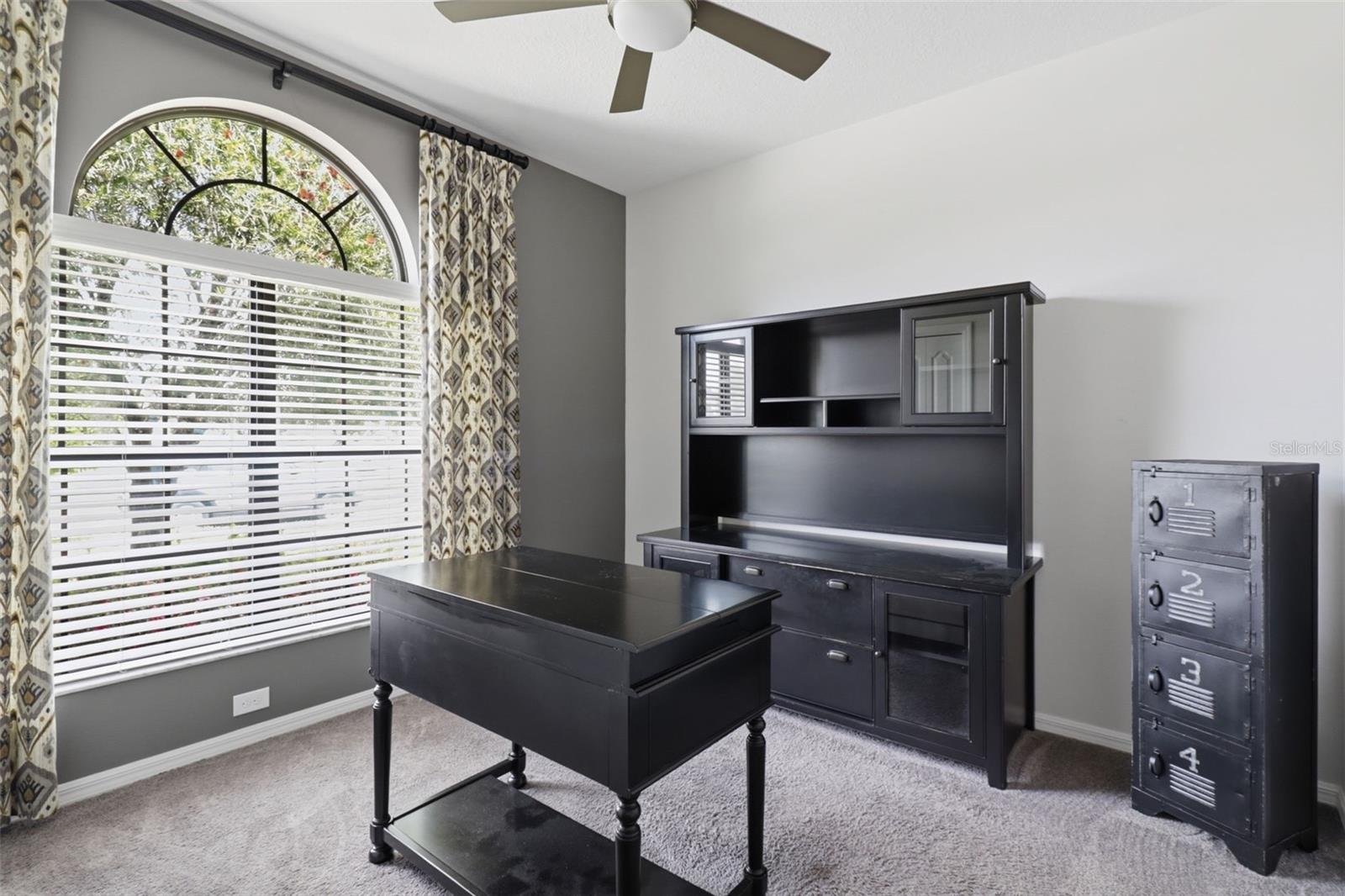 Bright and private room with large arched window, ideal as a home office, guest room, or additional bedroom.