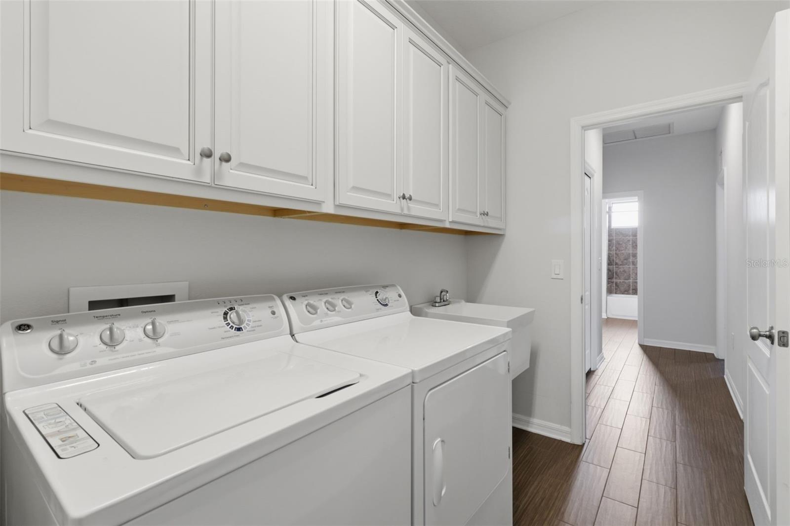 Interior laundry room with washer and dryer included, utility sink, and built-in cabinetry for added storage and convenience.