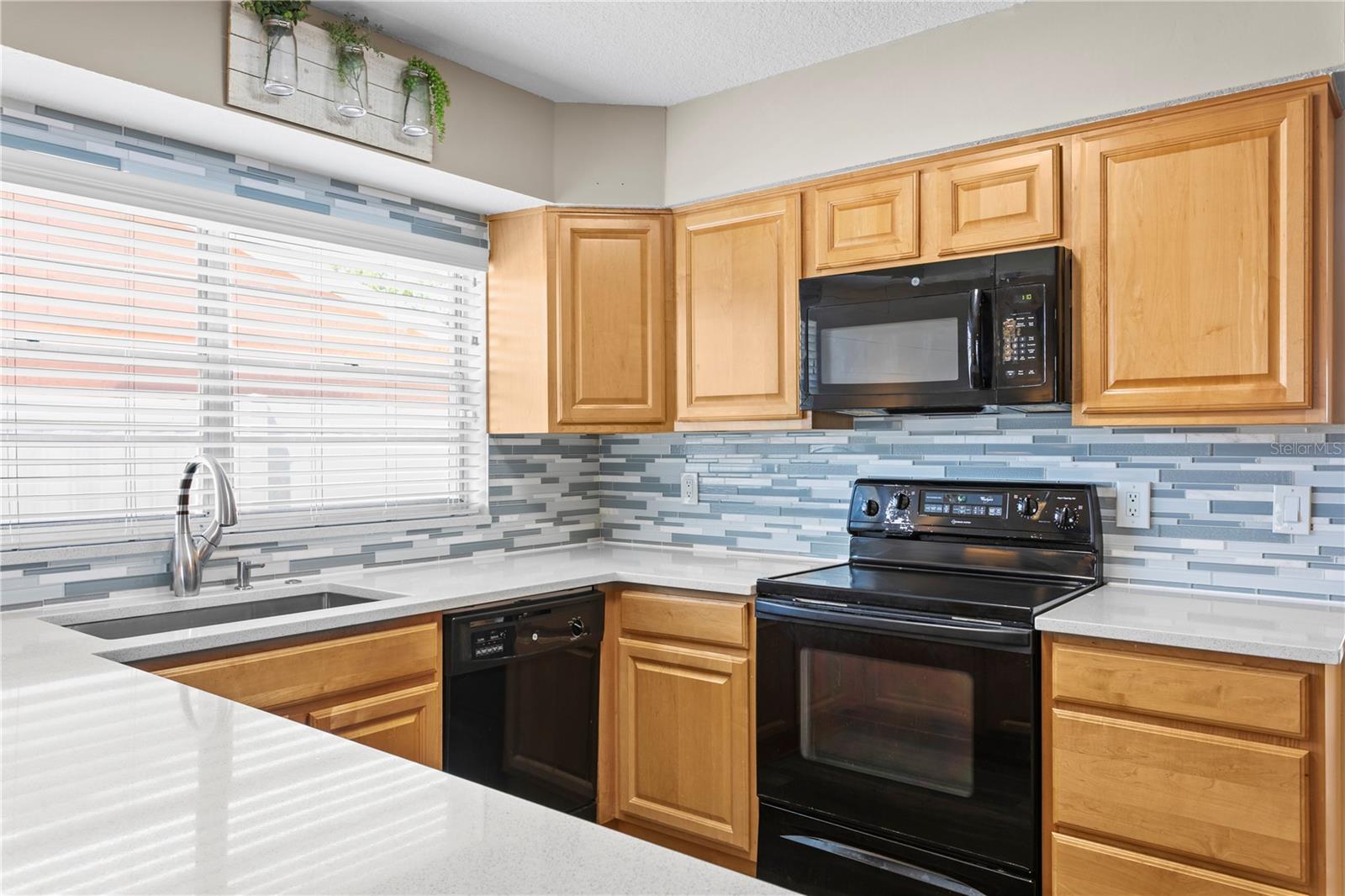 Kitchen features quartz counter tops and glass tile backsplash