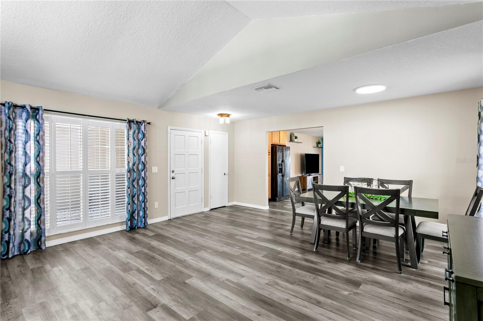 Large living room features luxury vinyl flooring and plantation shutters