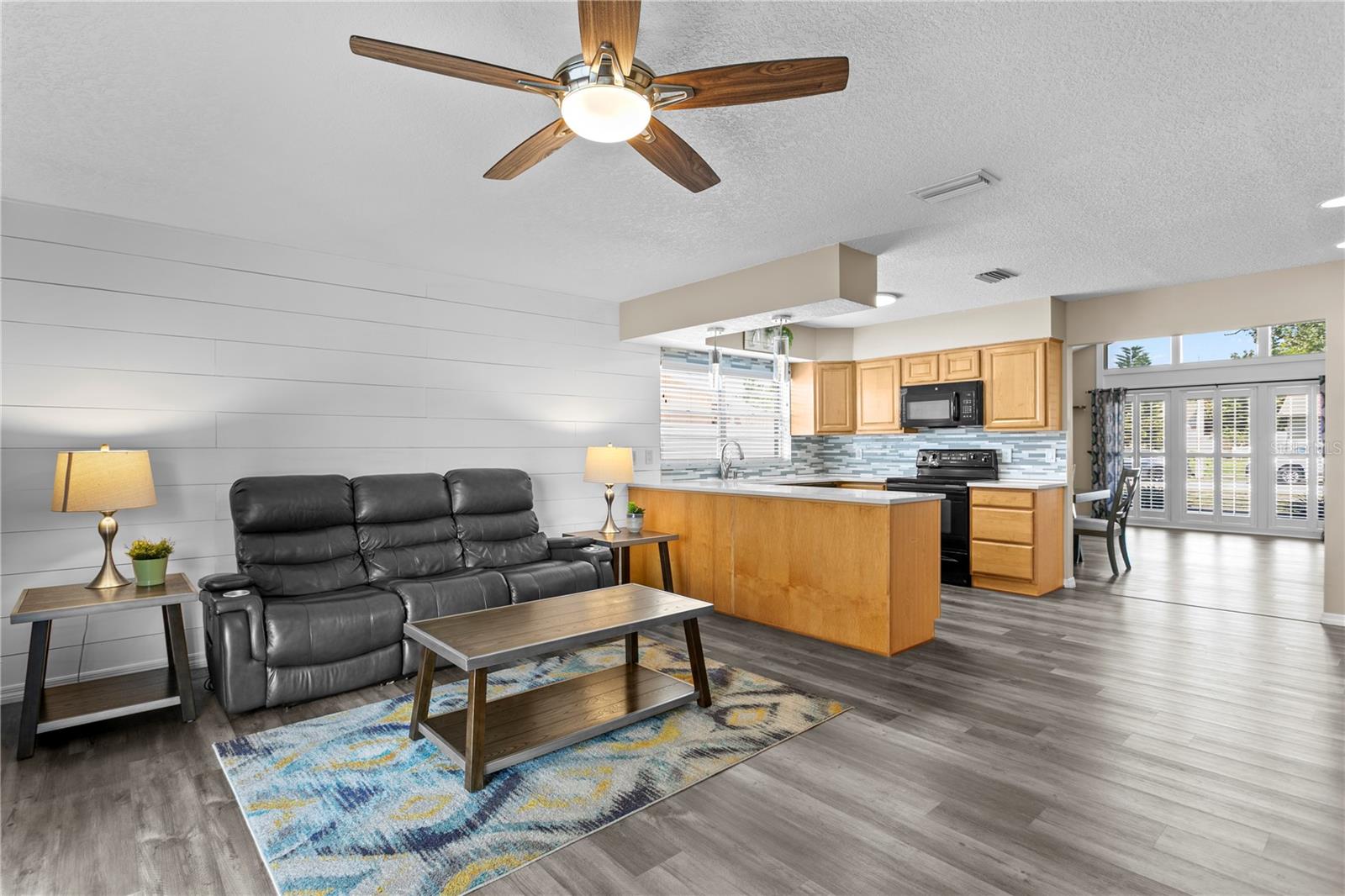 Family room features accent wall and ceiling fan