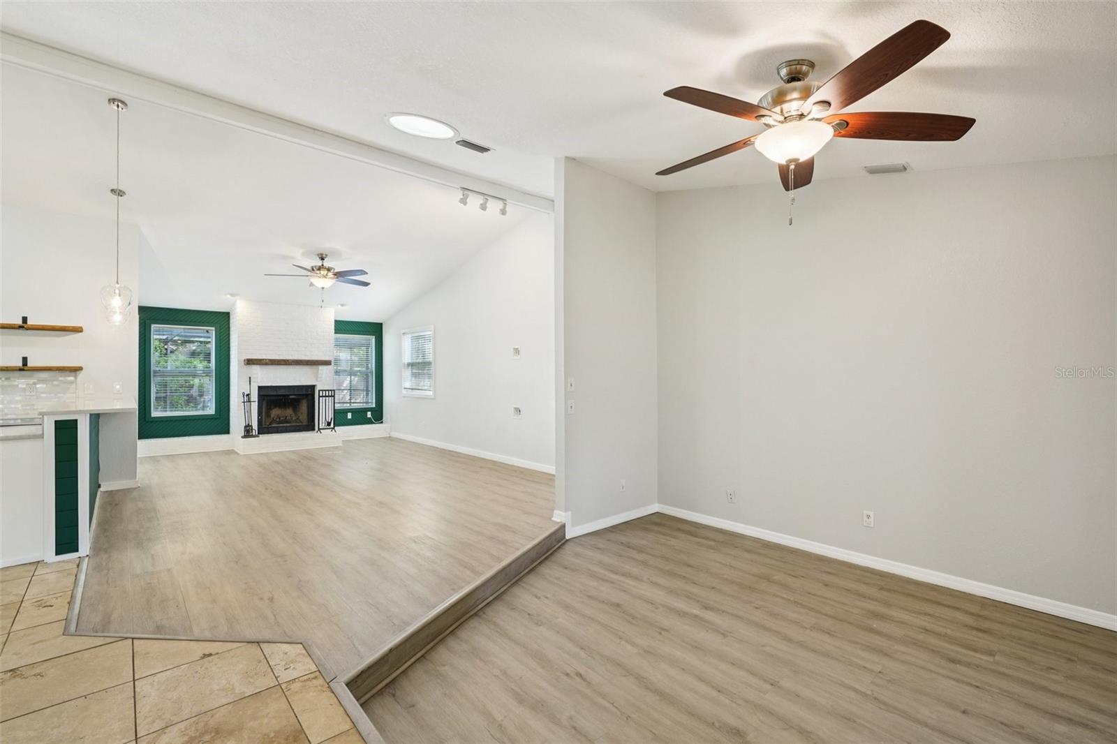 Living room into family room offering laminate flooring, vaulted ceilings and solar tube skylight.