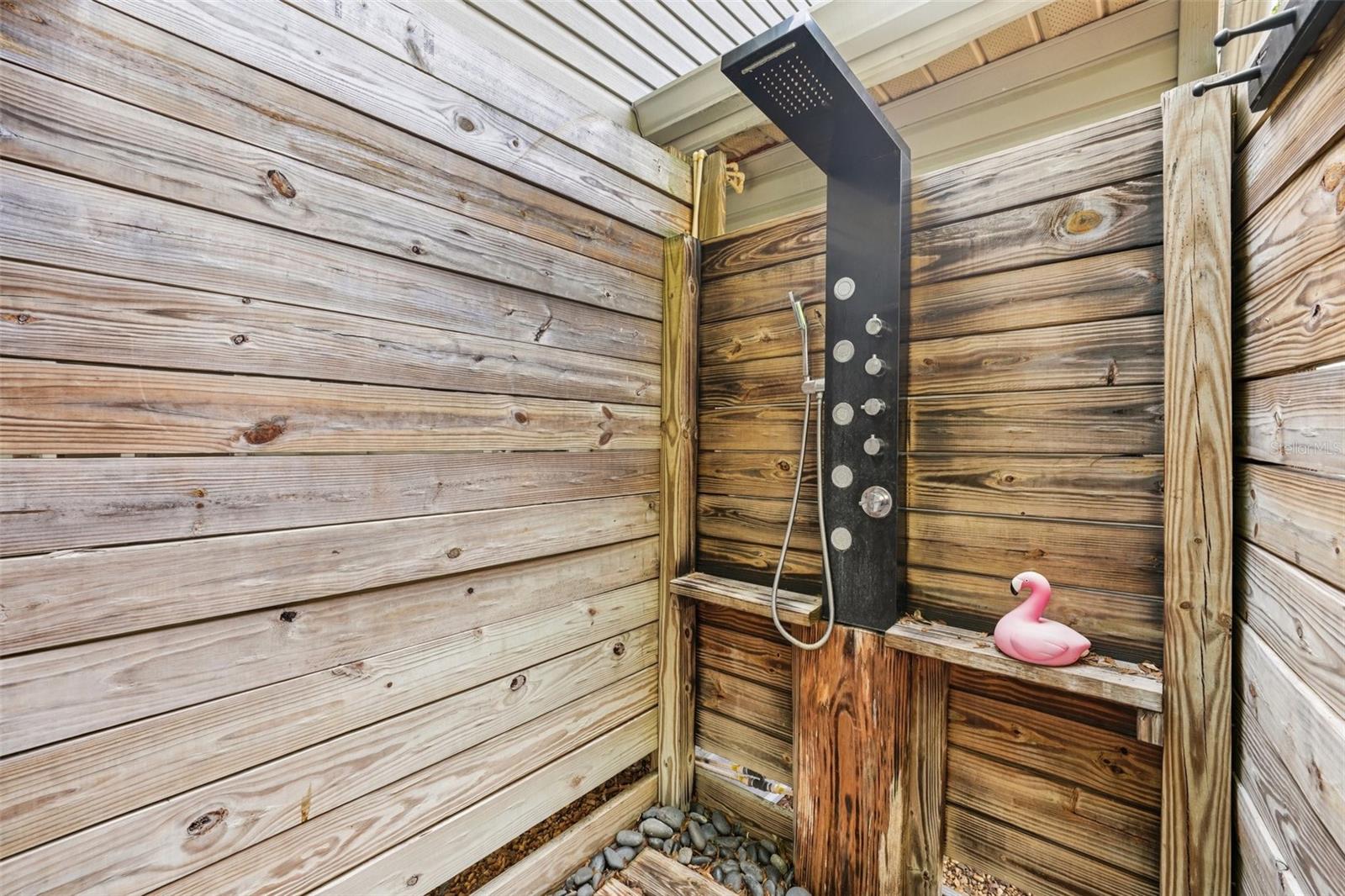 Poolside enclosed shower with rain and hand held shower nozzles.