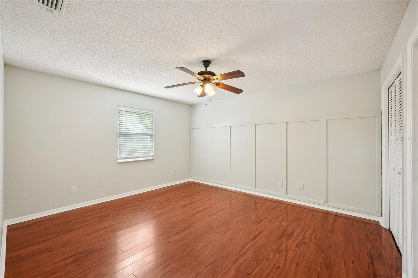 Second bedroom with laminate flooring, wall of closets and decorative box molding accent wall.