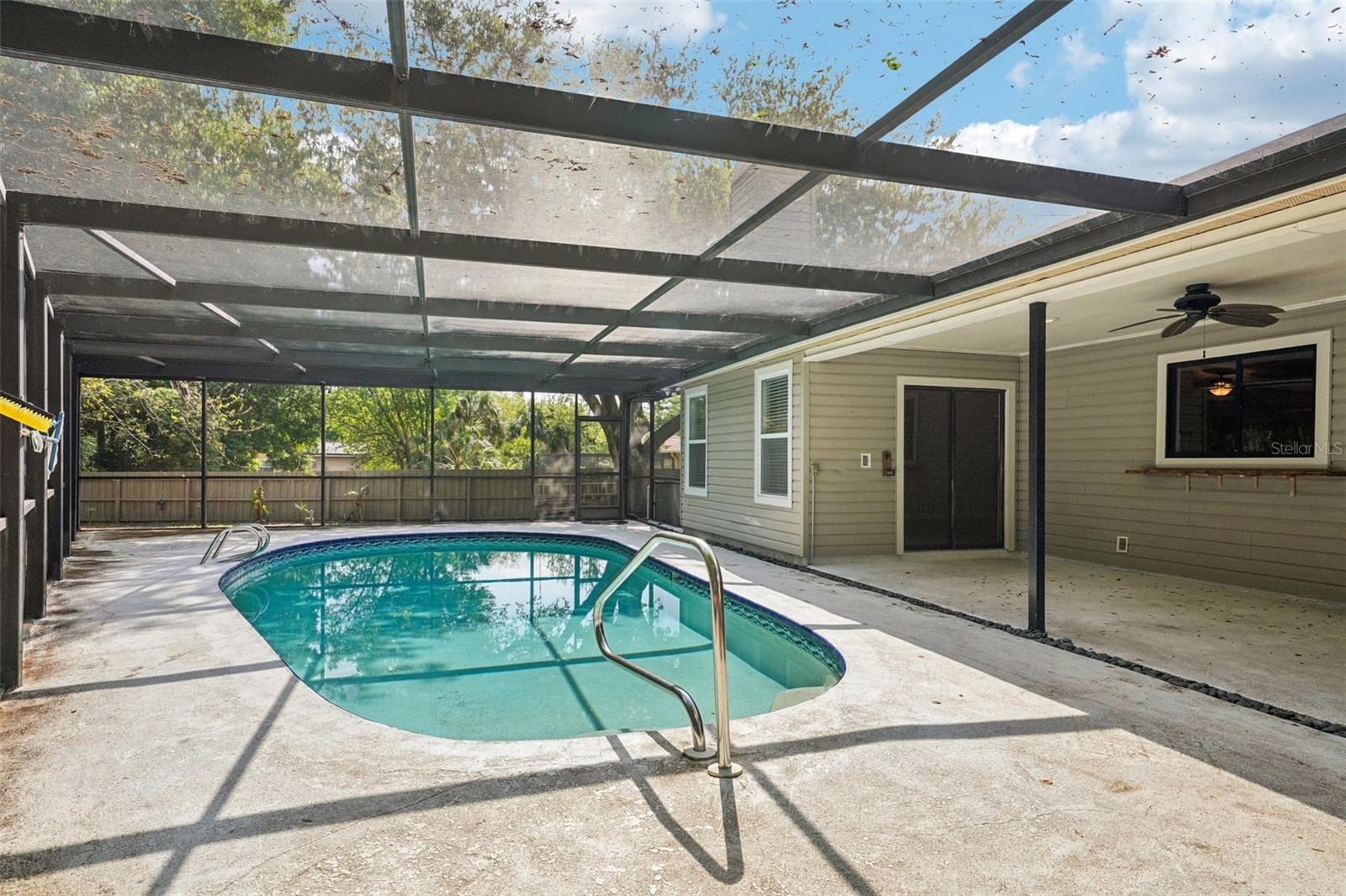 The screened-in pool area includes a covered area to sit and relax with a sparkling Pebble Tec pool to cool off in and enjoy the Florida weather.