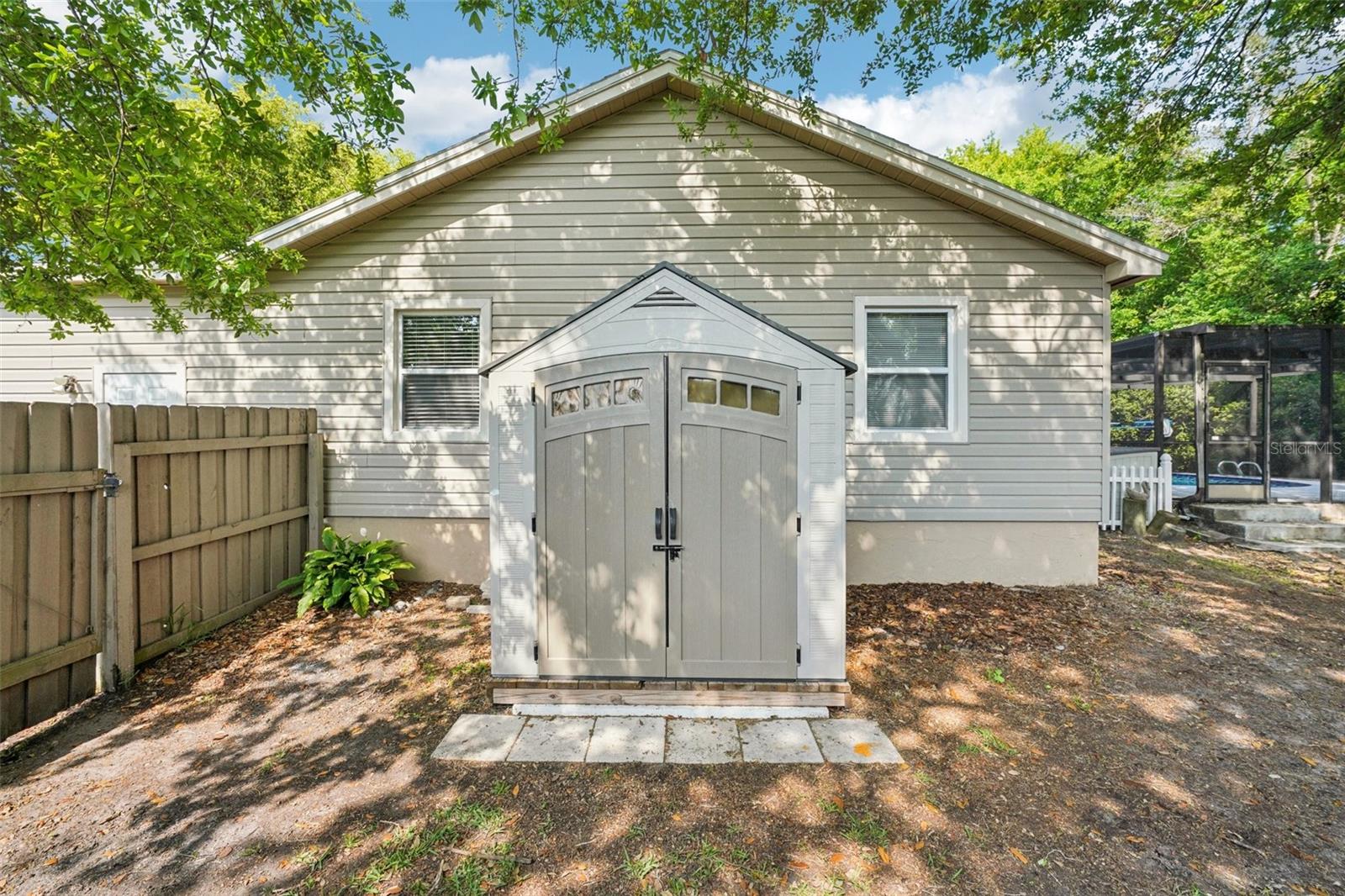 The expansive, fully fenced backyard features an enclosed outdoor shower area just off the pool with a rain shower head and handheld nozzle, while the side yards offer plenty of space to roam or garden, a playset, a swing under the mature oak, and a fire pit to gather around on cooler evenings.