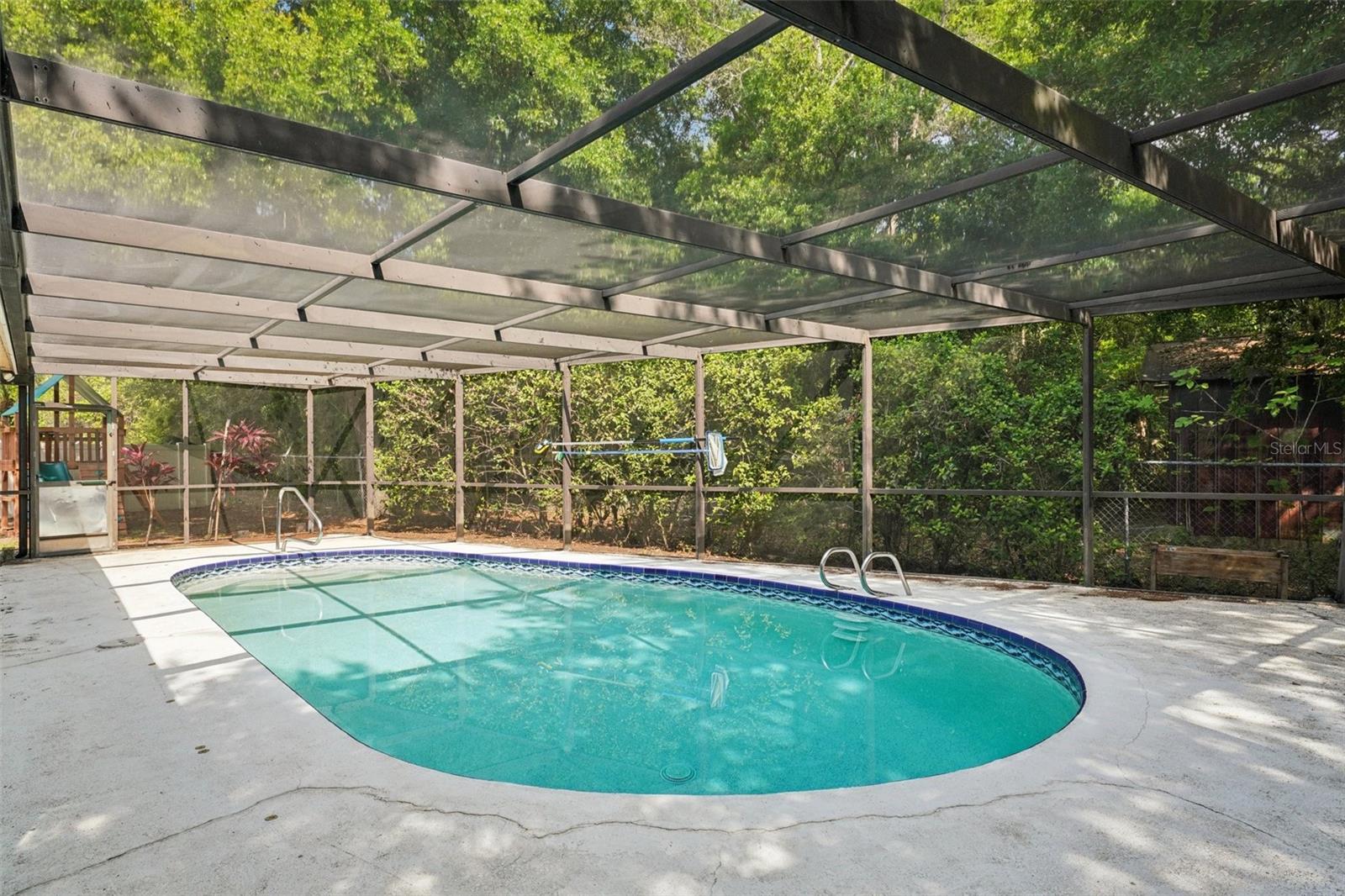 The screened-in pool area includes a covered area to sit and relax with a sparkling Pebble Tec pool to cool off in and enjoy the Florida weather.
