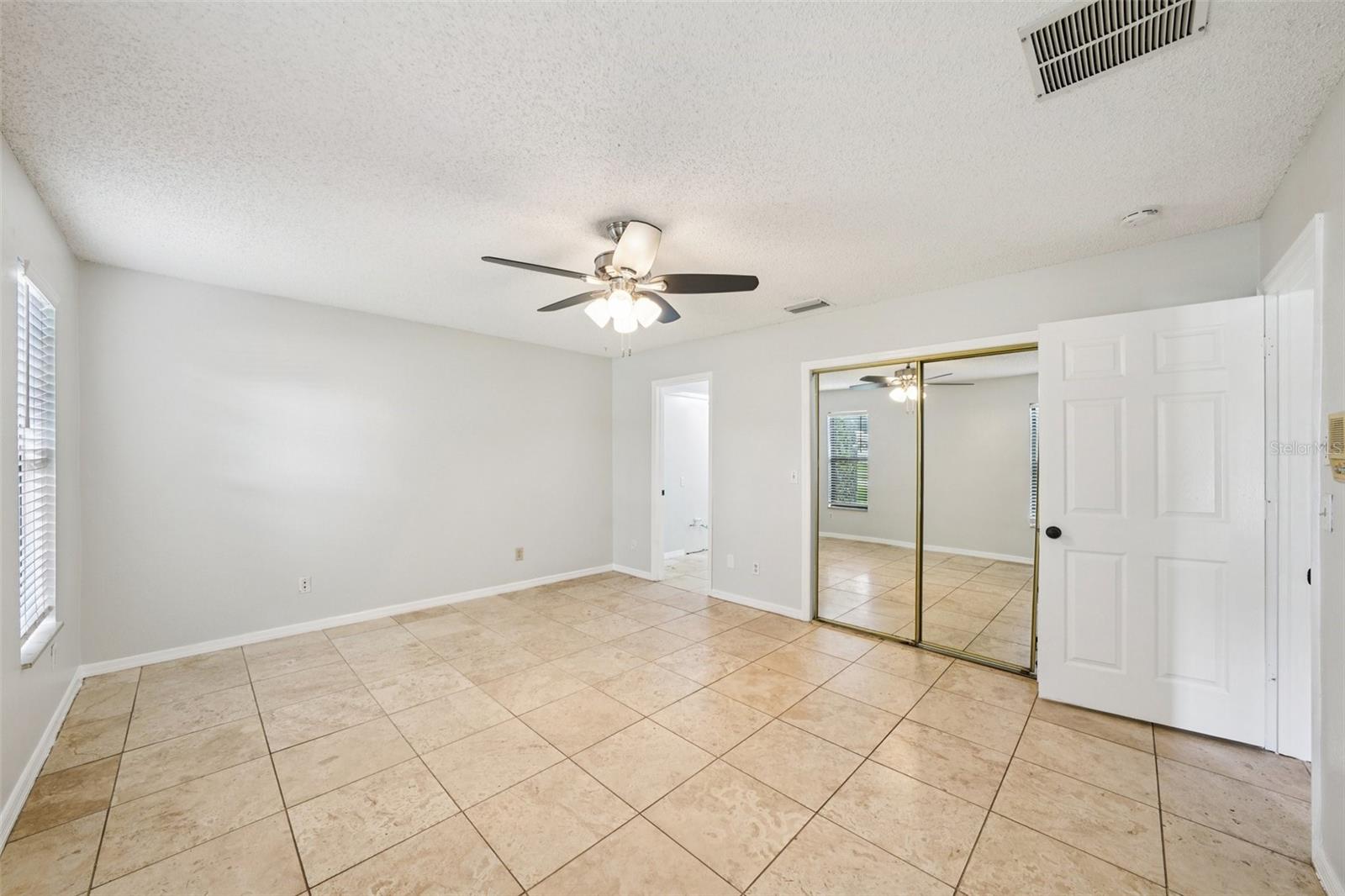 The primary suite boasts travertine flooring, an oversized walk-in closet, and an en-suite bathroom with a walk-in shower surrounded by beautiful travertine tile, and a brand-new dual-sink vanity.