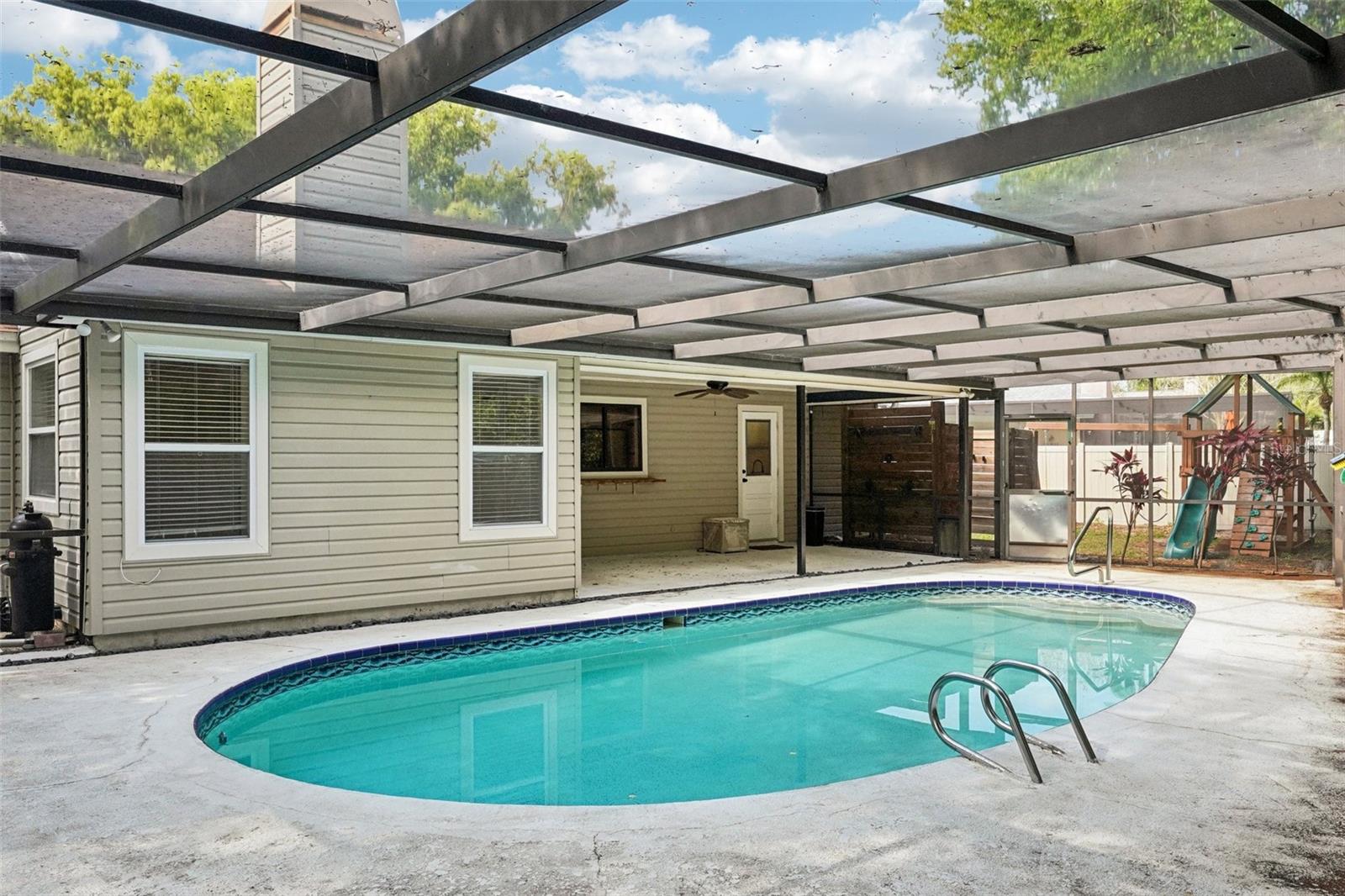 The screened-in pool area includes a covered area to sit and relax with a sparkling Pebble Tec pool to cool off in and enjoy the Florida weather.