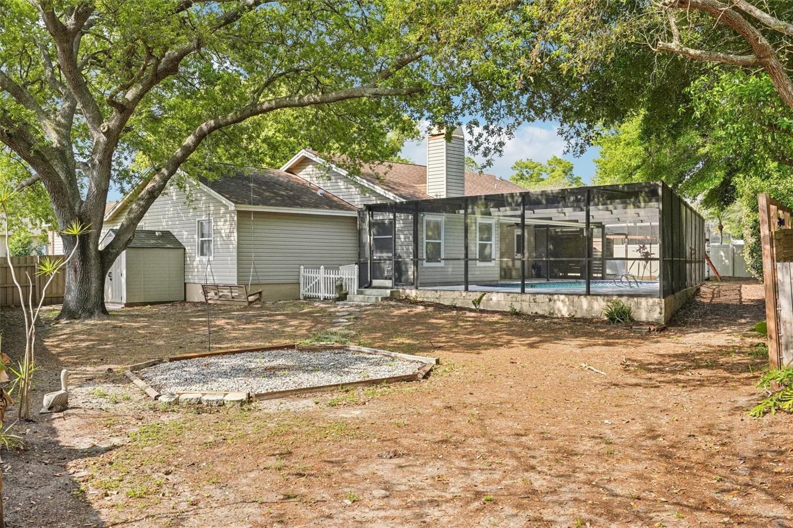 The expansive, fully fenced backyard features an enclosed outdoor shower area just off the pool with a rain shower head and handheld nozzle, while the side yards offer plenty of space to roam or garden, a playset, a swing under the mature oak, and a fire pit to gather around on cooler evenings.