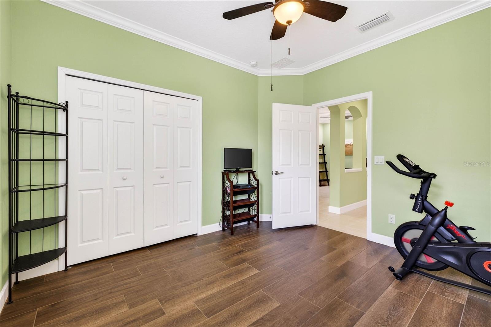 Secondary bedroom with built in closet, crown molding and ceiling fan.