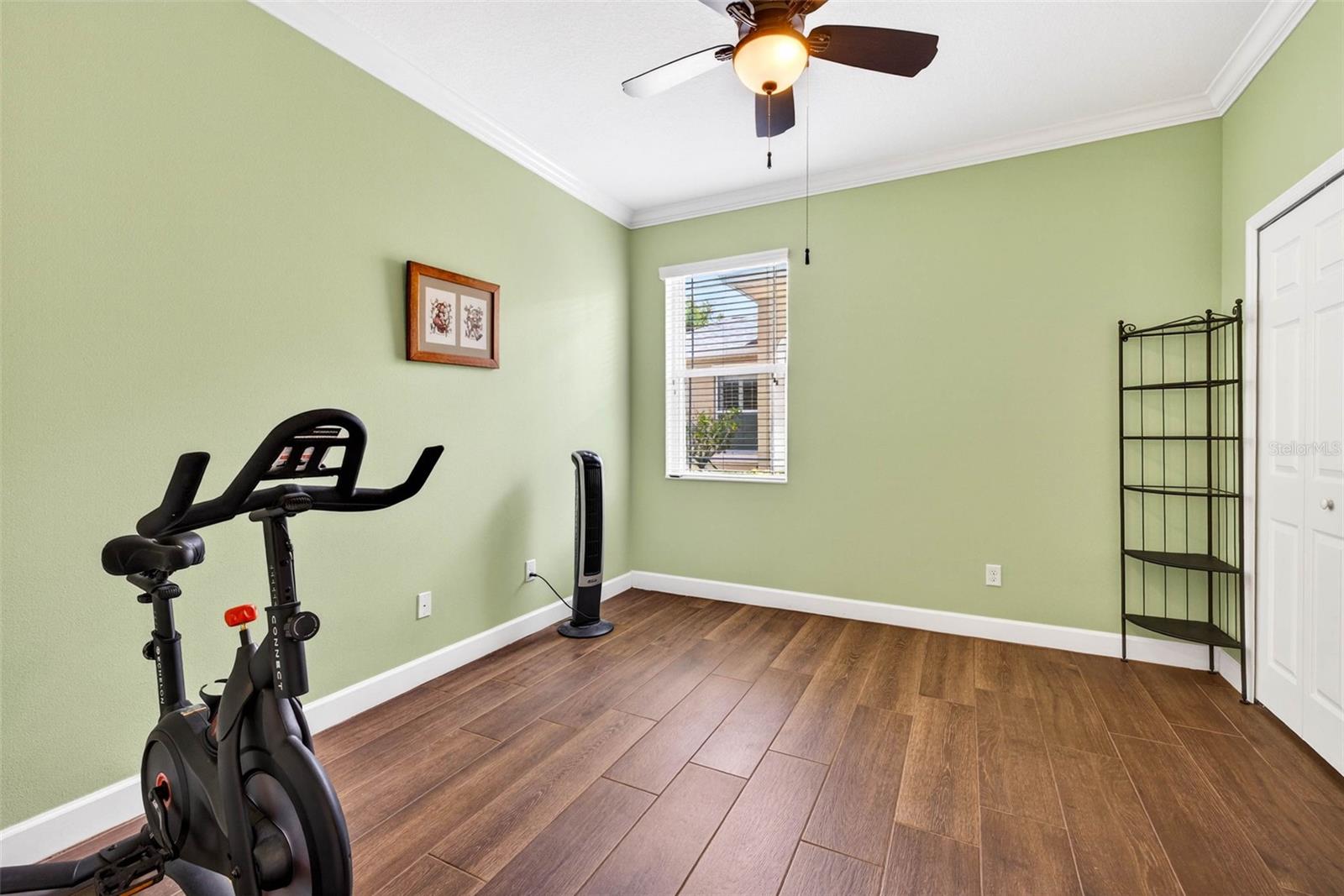 Secondary bedroom with ceiling fan and crown molding.