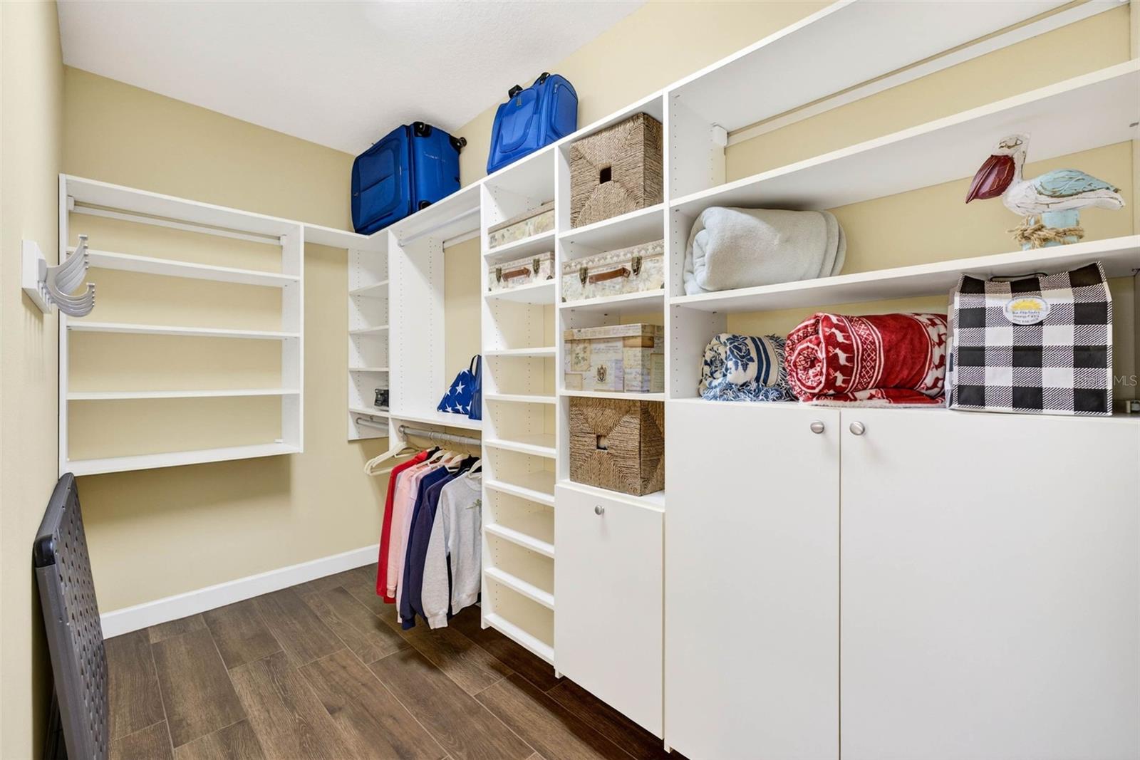 Primary closet with built in shelves and cabinets.