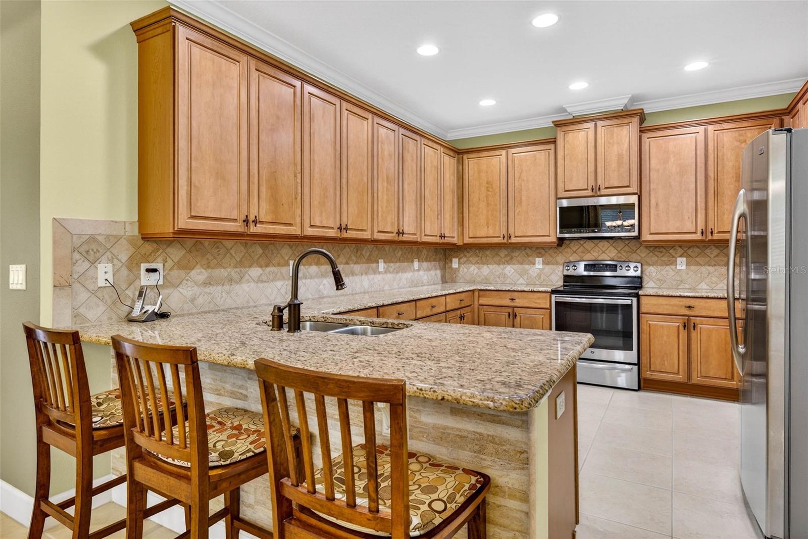 Functional kitchen with plenty of countertop space and cabinets for storage. Decorative wall at breakfast bar.