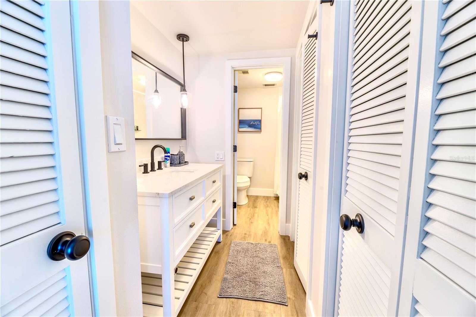 (Left to Right) Towel Closet, Single Vanity with Quartz countertops, Toilet & Shower tub, 2 closets on right