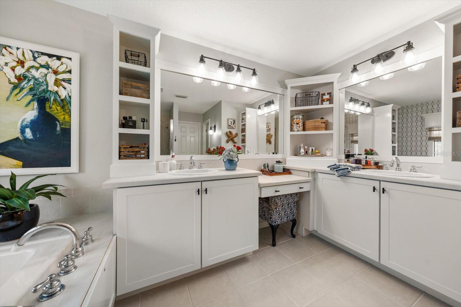 Primary en suite bath with custom shelving, dual sinks, vanity, garden tub