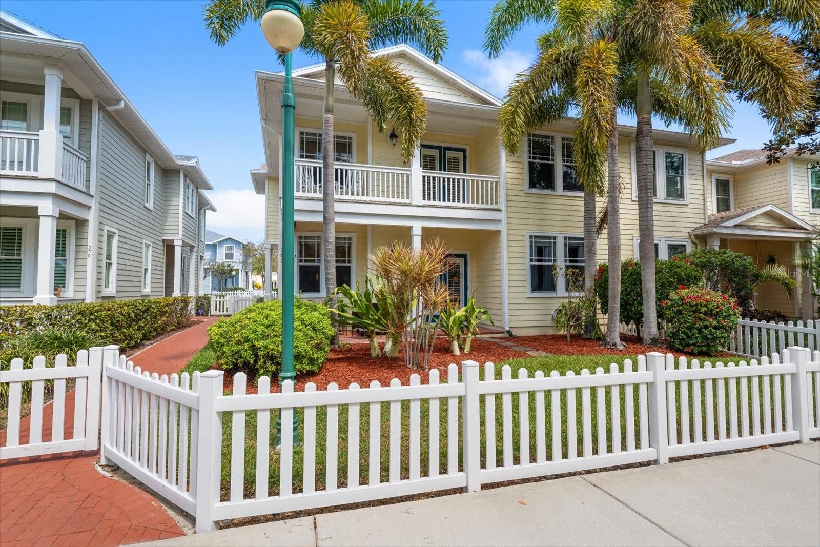 Front of unit, brick walkway, fenced front yard, french doors, balcony from primary suite