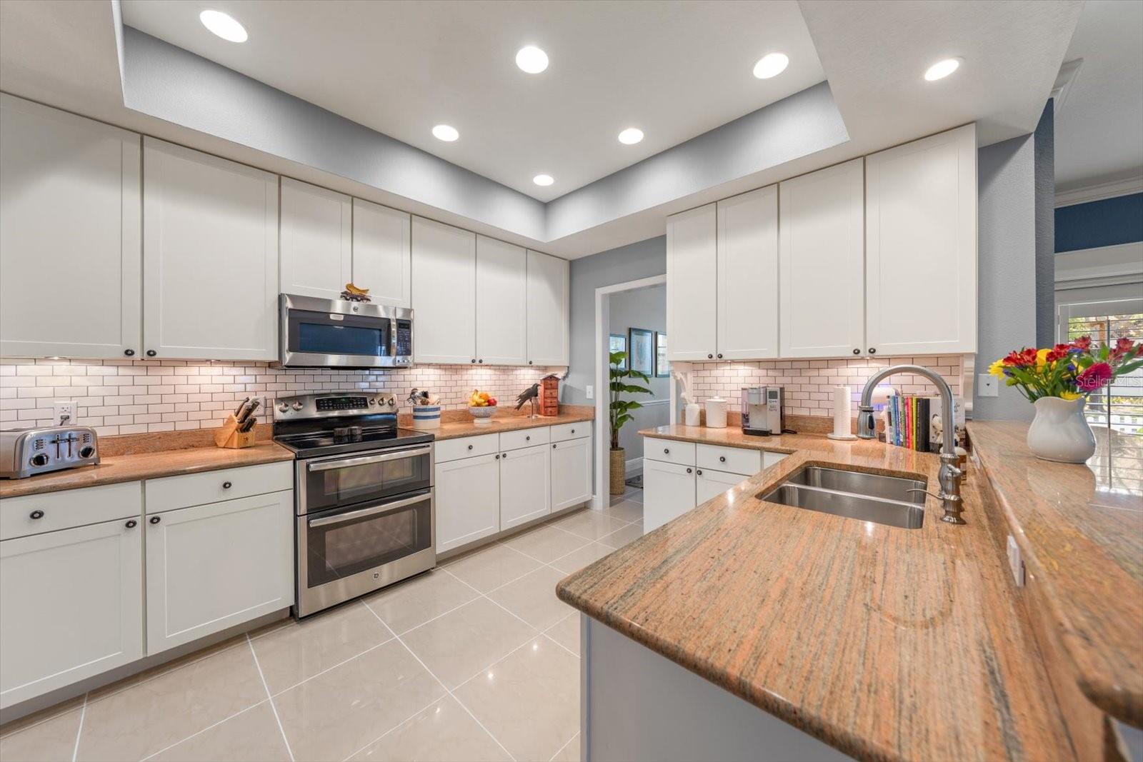 Kitchen with tray ceiling, granite, breakfast bar, tiled backsplash