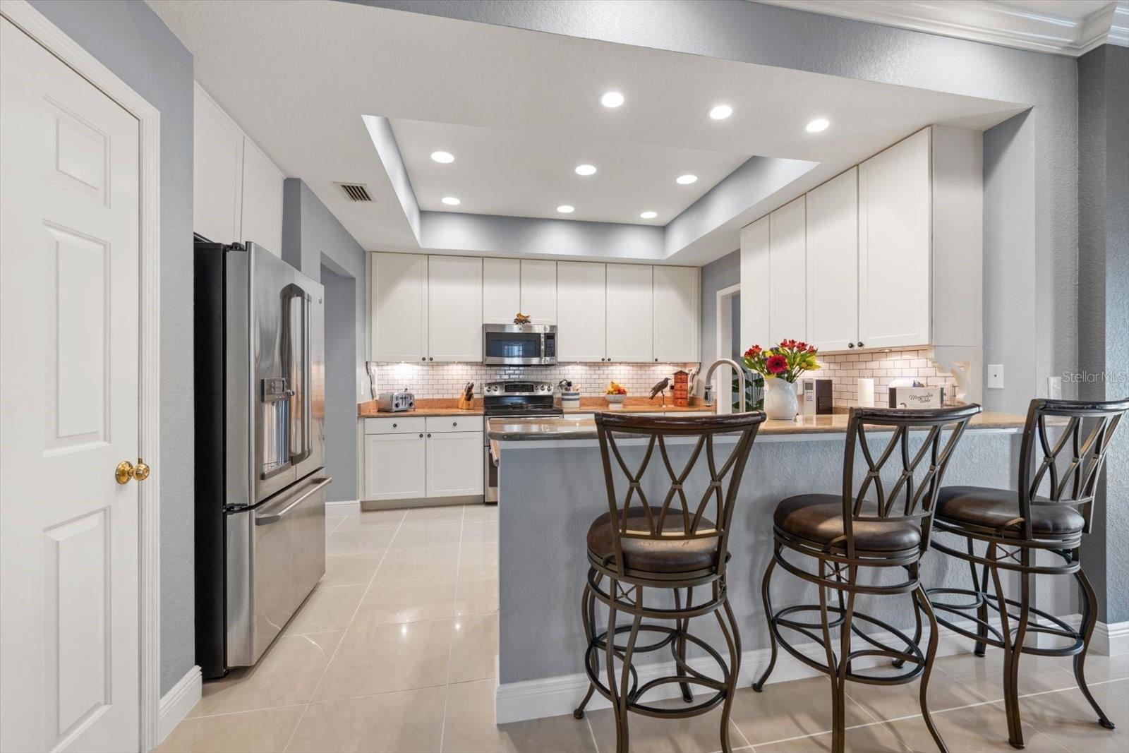 Kitchen with tile backsplash, tray ceiling, breakfast bar, 3 closet pantries