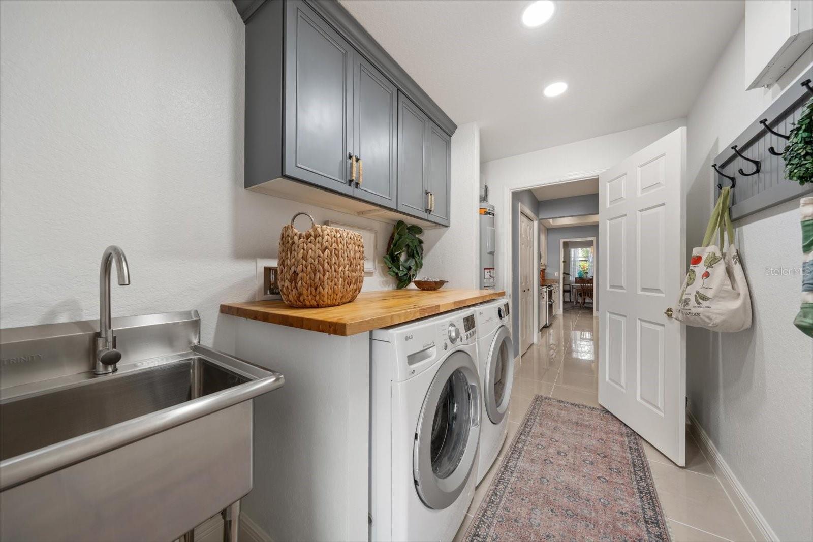 Laundry room with butcher block countertop, cabinetry and utility sink
