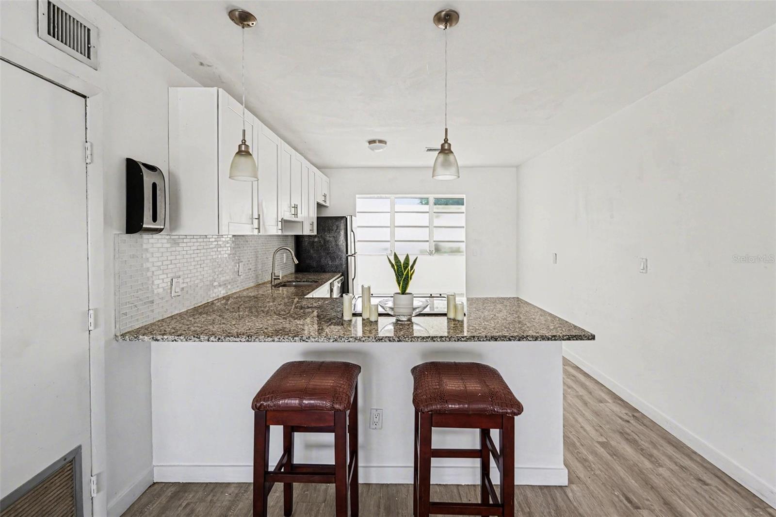 The kitchen features granite countertop, tile backsplash, new custom cabinets and stainless steel appliances