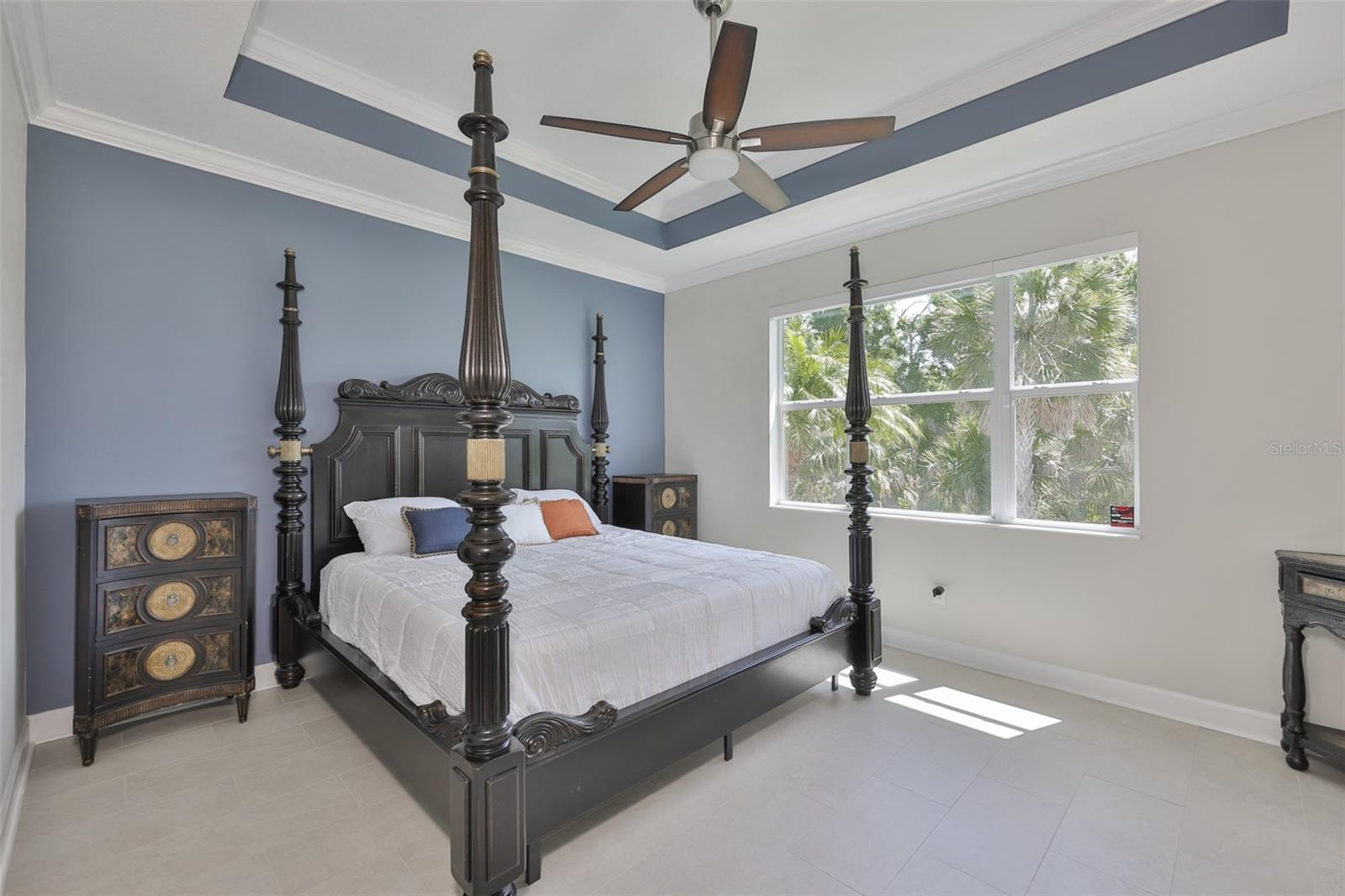 Primary bedroom is large with trey ceiling and tile floors.