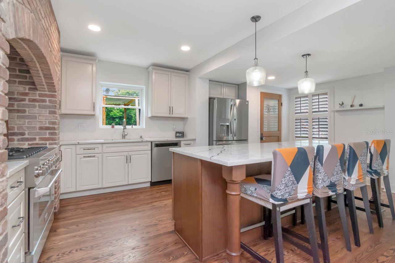 Chef's Kitchen with upgraded Stainless Steel Appliances, Exapnsive Island, Window over the Sink, Custom Pantry Door, and Hardwood Floors.