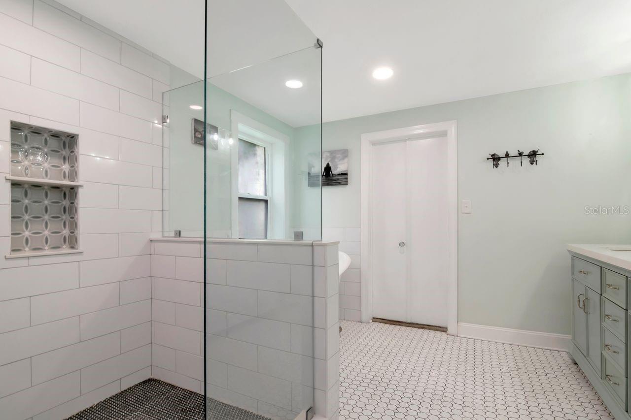 Shower Stall with Decorative Inset and Entry to Primary Bedroom.