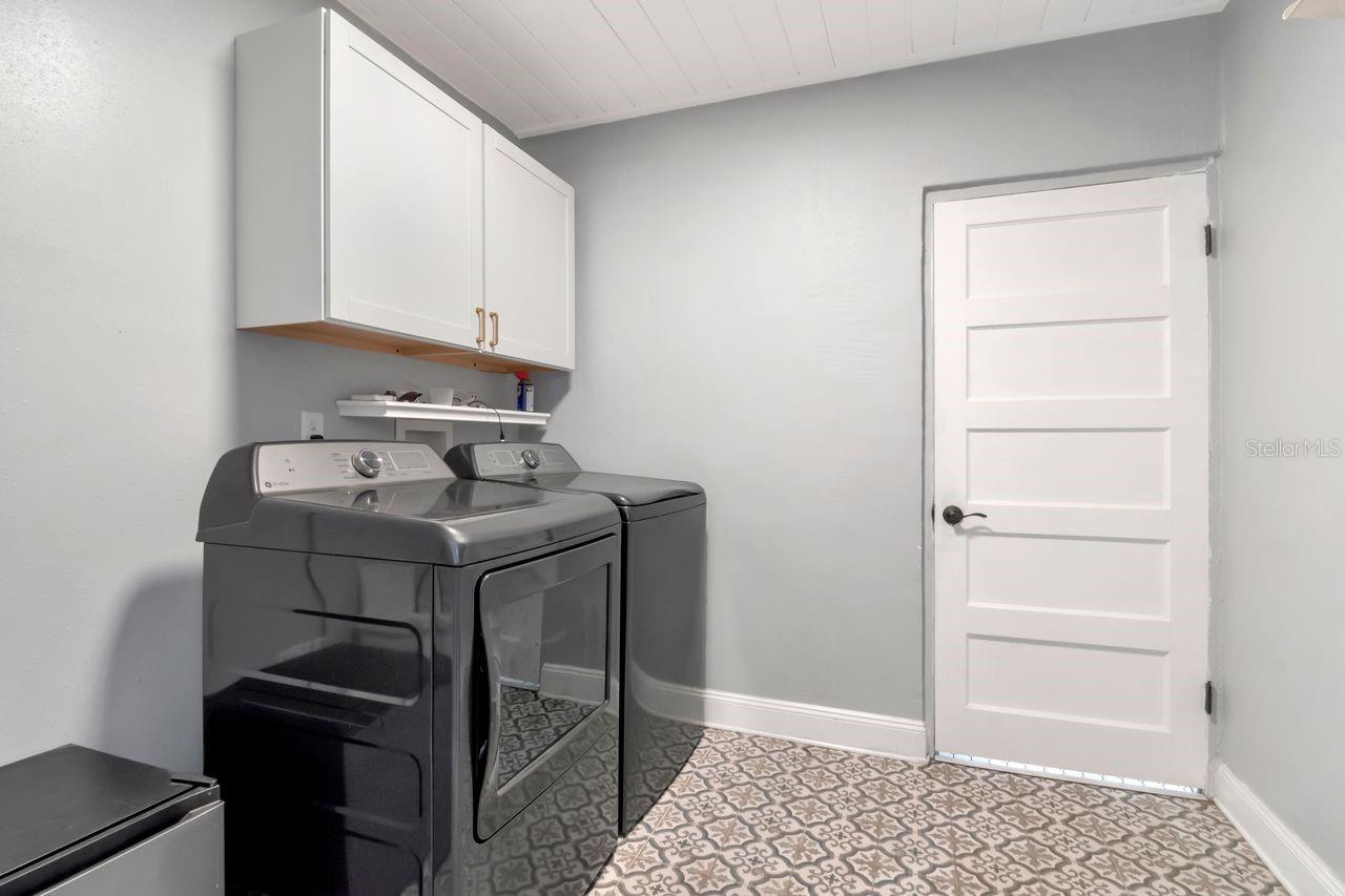 Inside Laundry Room with Access to the Primary Bathroom and Kitchen, Decorative/Upgraded Tile Floor, Cabinets and Shelving installed.