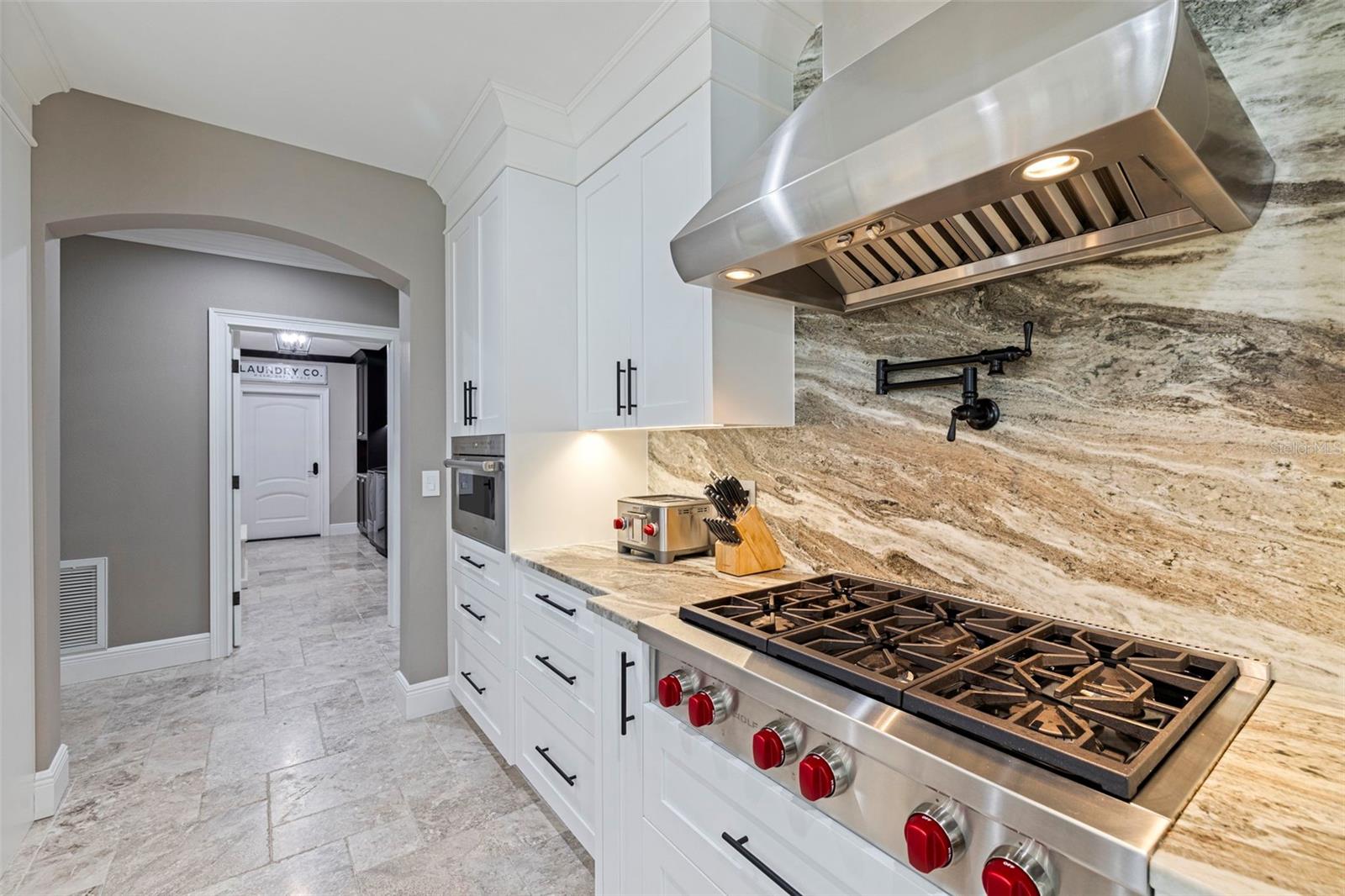 Chef’s kitchen with high-end appliances, custom hood, and detailed backsplash