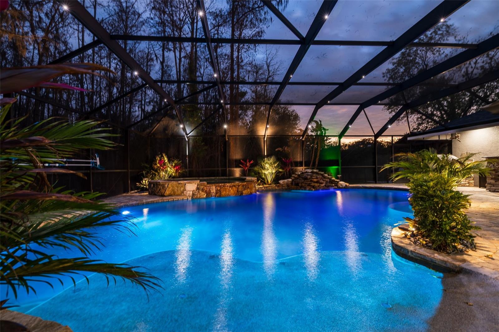 Resort-style pool illuminated at night creating a private backyard oasis