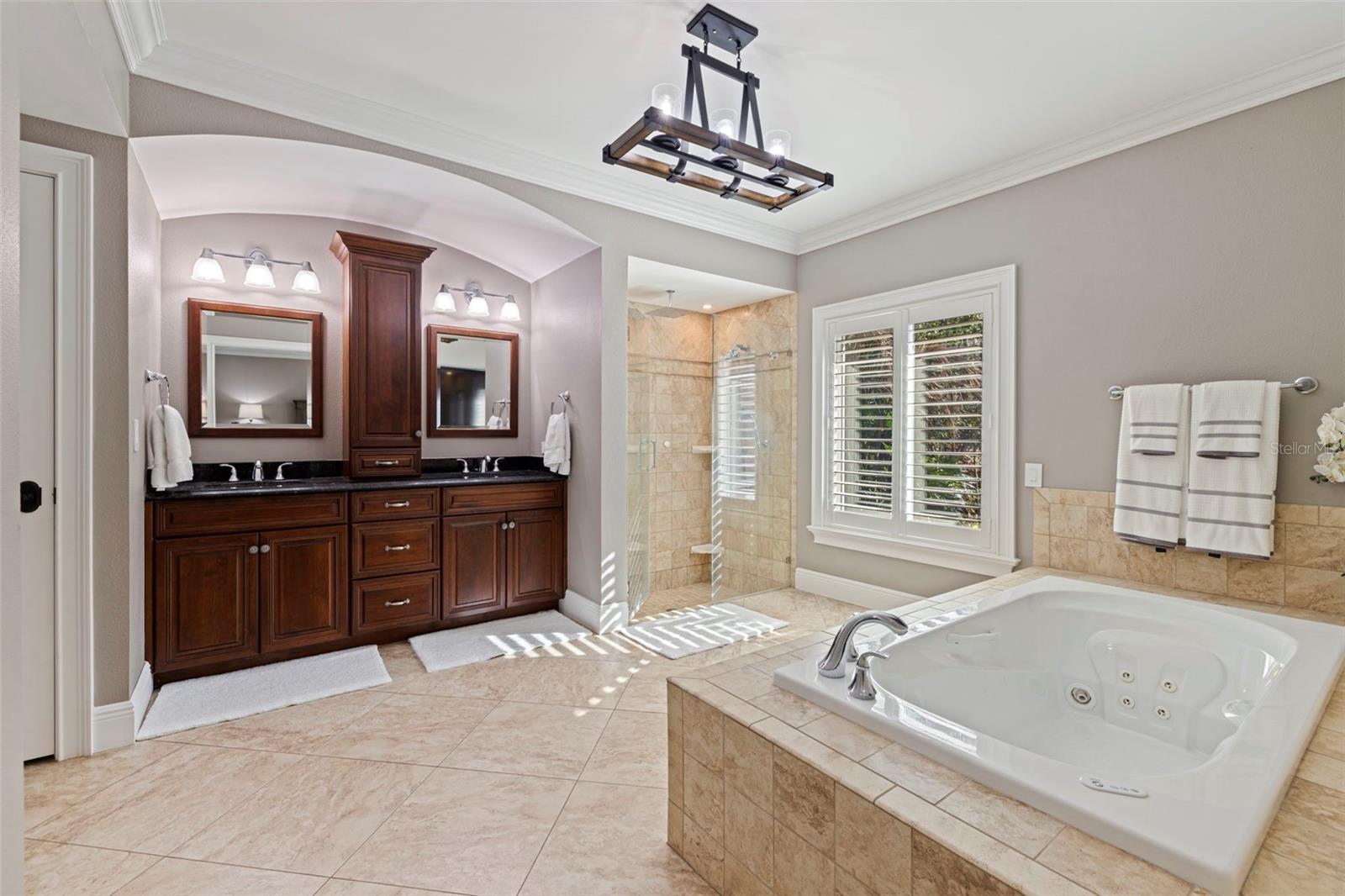 Primary bathroom featuring dual vanities, soaking tub, and separate shower
