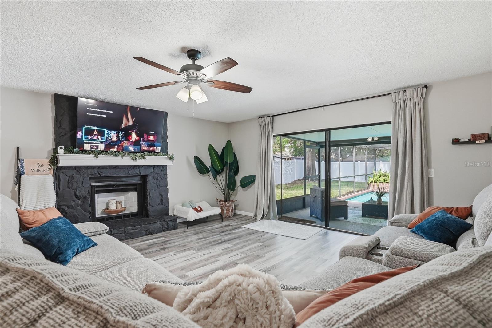 Spacious living space with wood burning fireplace and sliders off to the pool